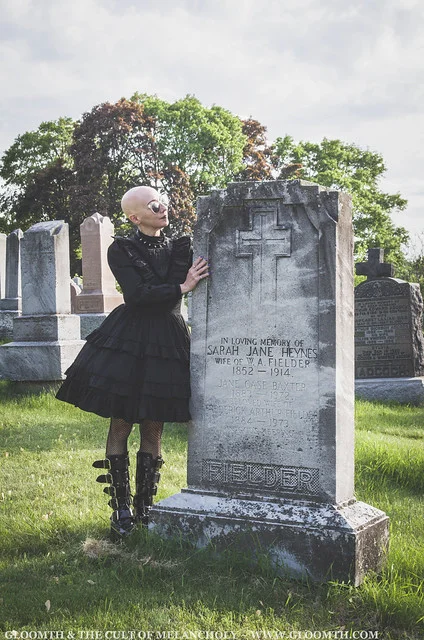 gothic woman leaning against tombstone