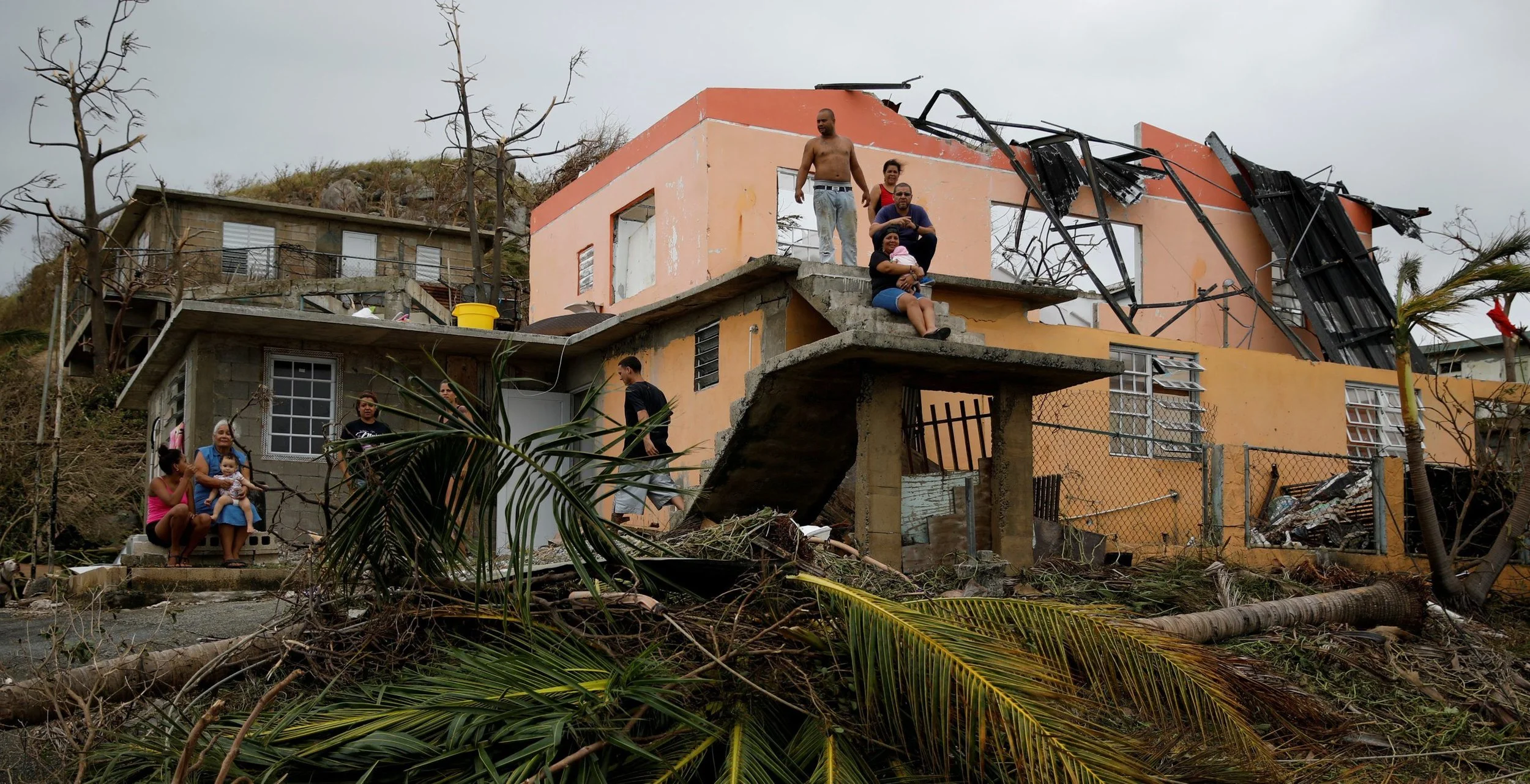 People rest outside a damaged house after the area was hit by Hurricane Maria in Yabucoa.