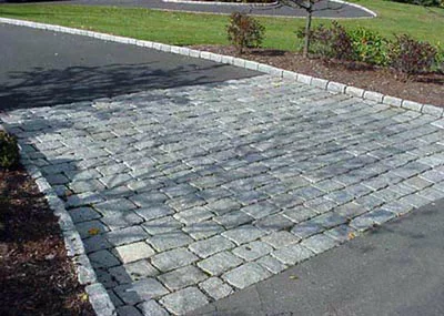 The blocks on this apron are flush with the road, but the edging blocks should not reach the roadway since plows will come into contact with them.