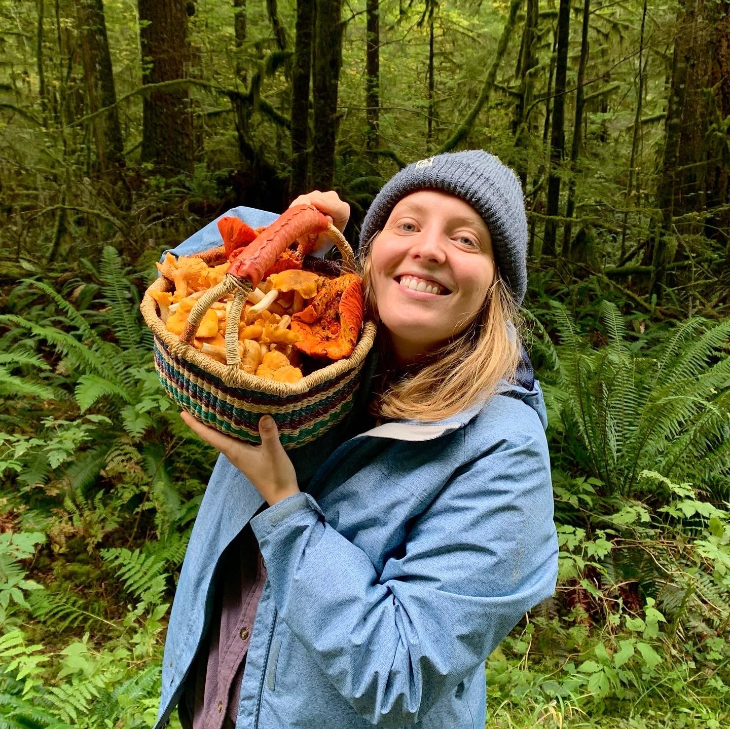 Stefanie smiling with a basket of mushrooms in a foest