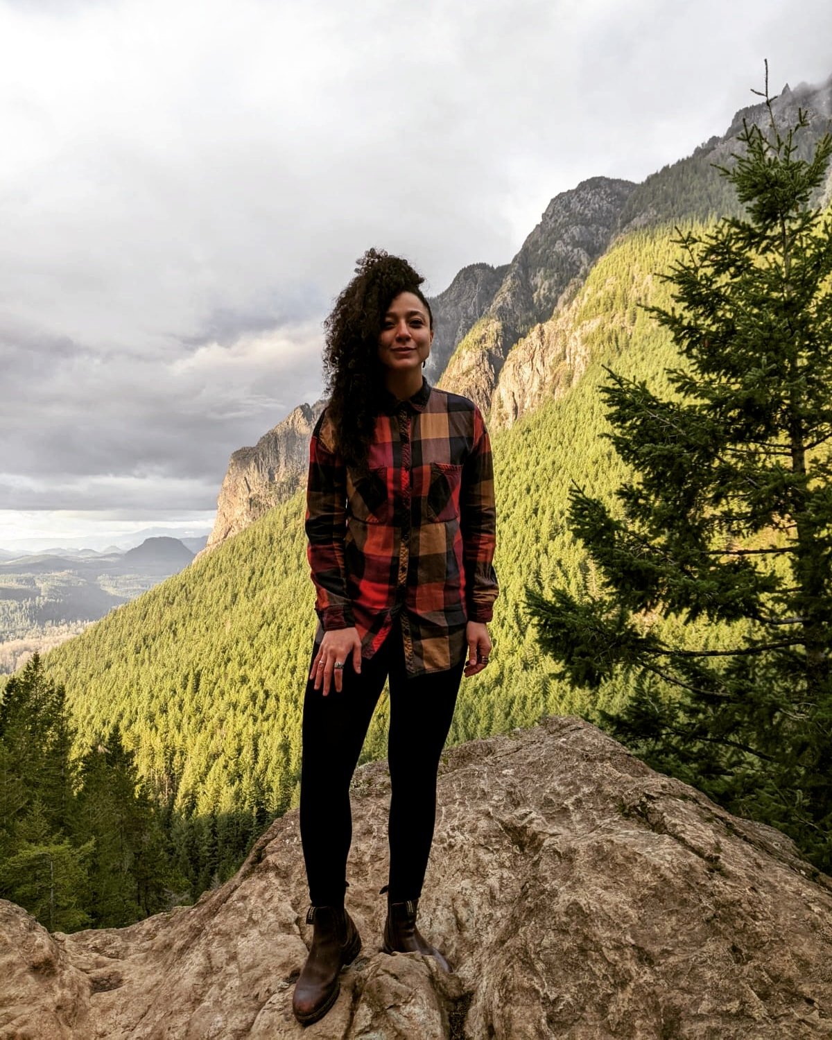 Woman standing on rocks overlooking mountains and valley