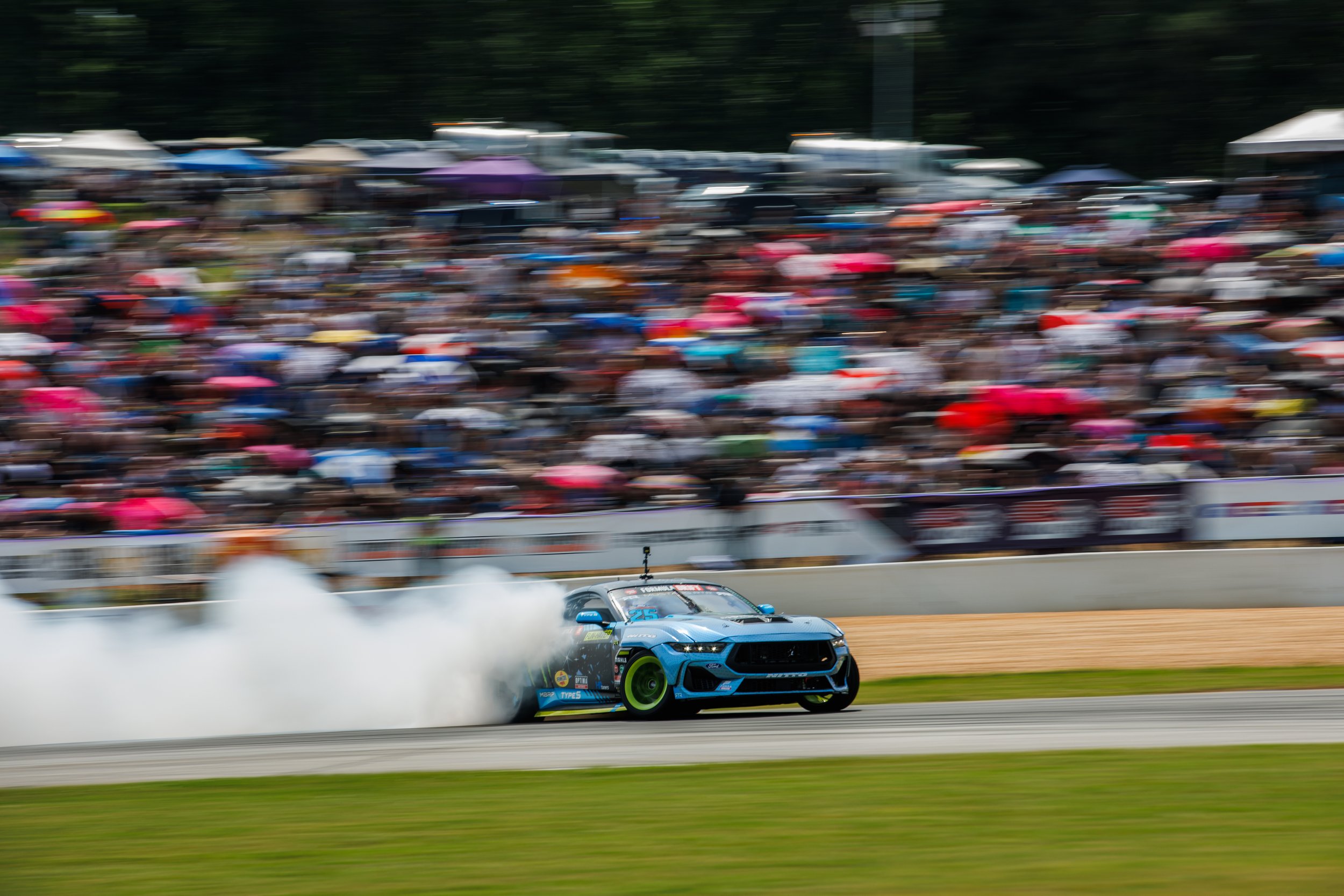 Vaughn Gittin Jr. drifts a Ford Mustang RTR Spec5-FD across the track with a trail of tire smoke. Photo featured in the new book "Ready To Rock." Photo by Larry Chen. Published by Carrara Media, 2026.