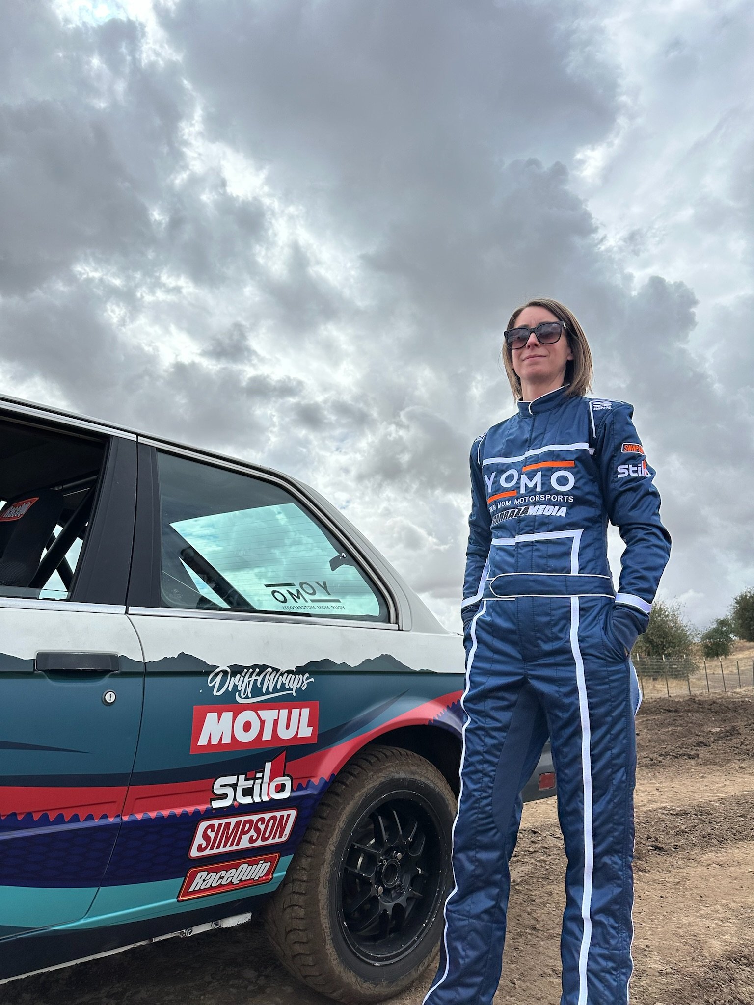 Kelly Conroy, author of the new book 'Your Mom Races Rally,' poses alongside the BMW E30 racecar named Nessie that she learned to build and race in an effort to rediscover fun in her life as a mother. Published by Carrara Media.