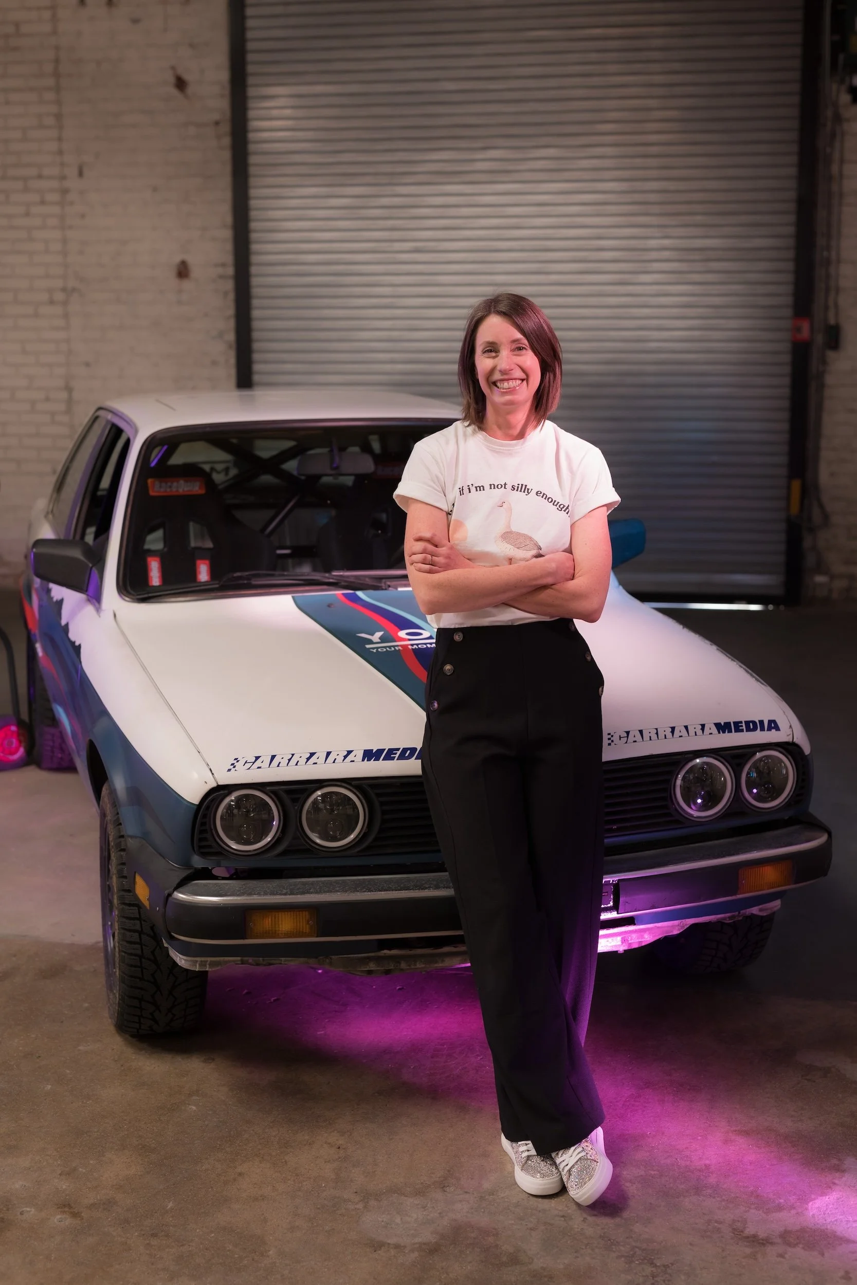 Kelly Conroy, author of "Your Mom Races Rally," poses with her BMW E30 rally car build nicknamed Nessie. Published by Carrara Media, 2026.