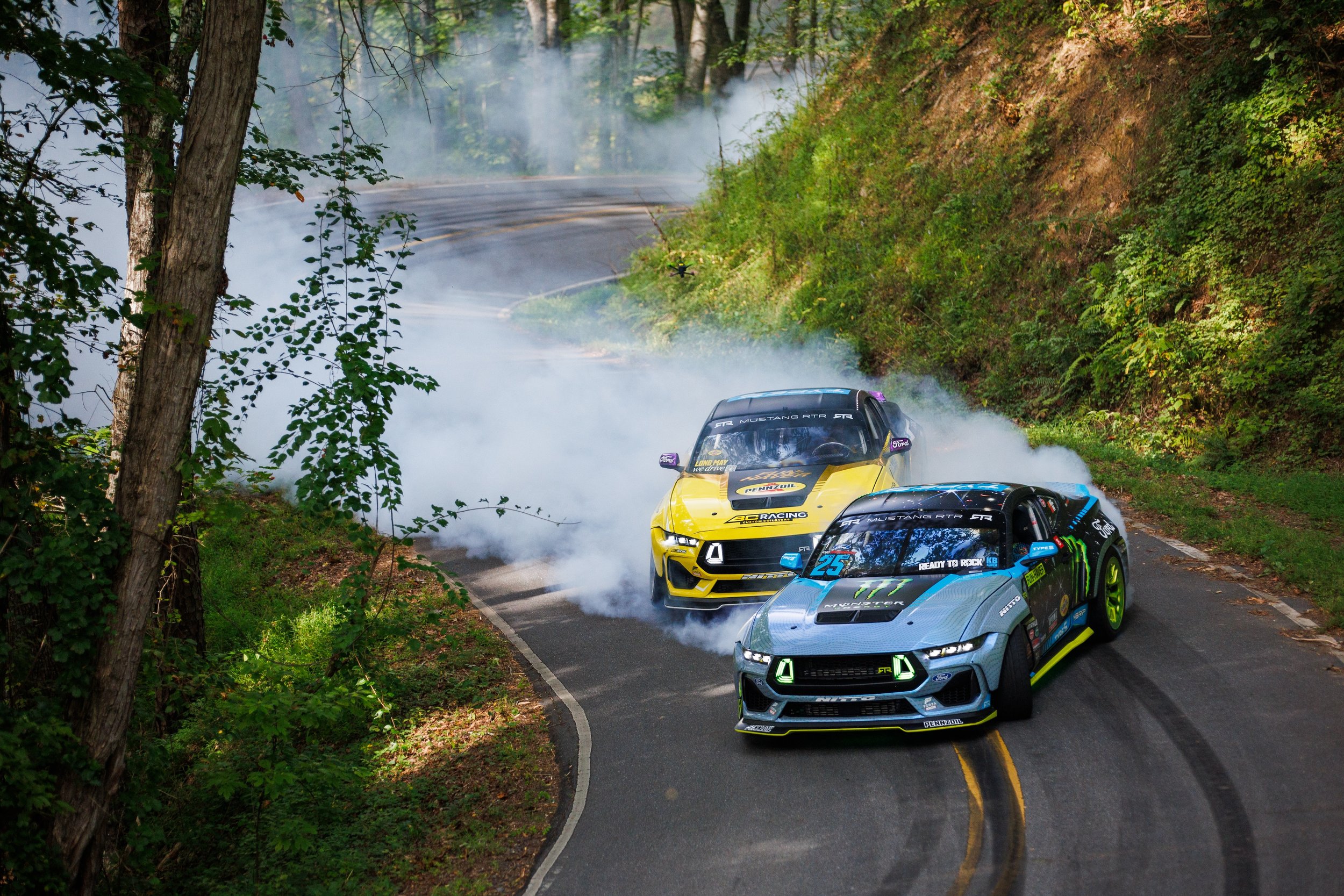 Vaughn Gittin Jr. and Chelsea DeNofa drift around a corner with a trail of tire smoke, in an image featured in Ready To Rock, the new book by Gittin Jr. about the rise of RTR Vehicles. Photo by Larry Chen. Published by Carrara Media, 2026.