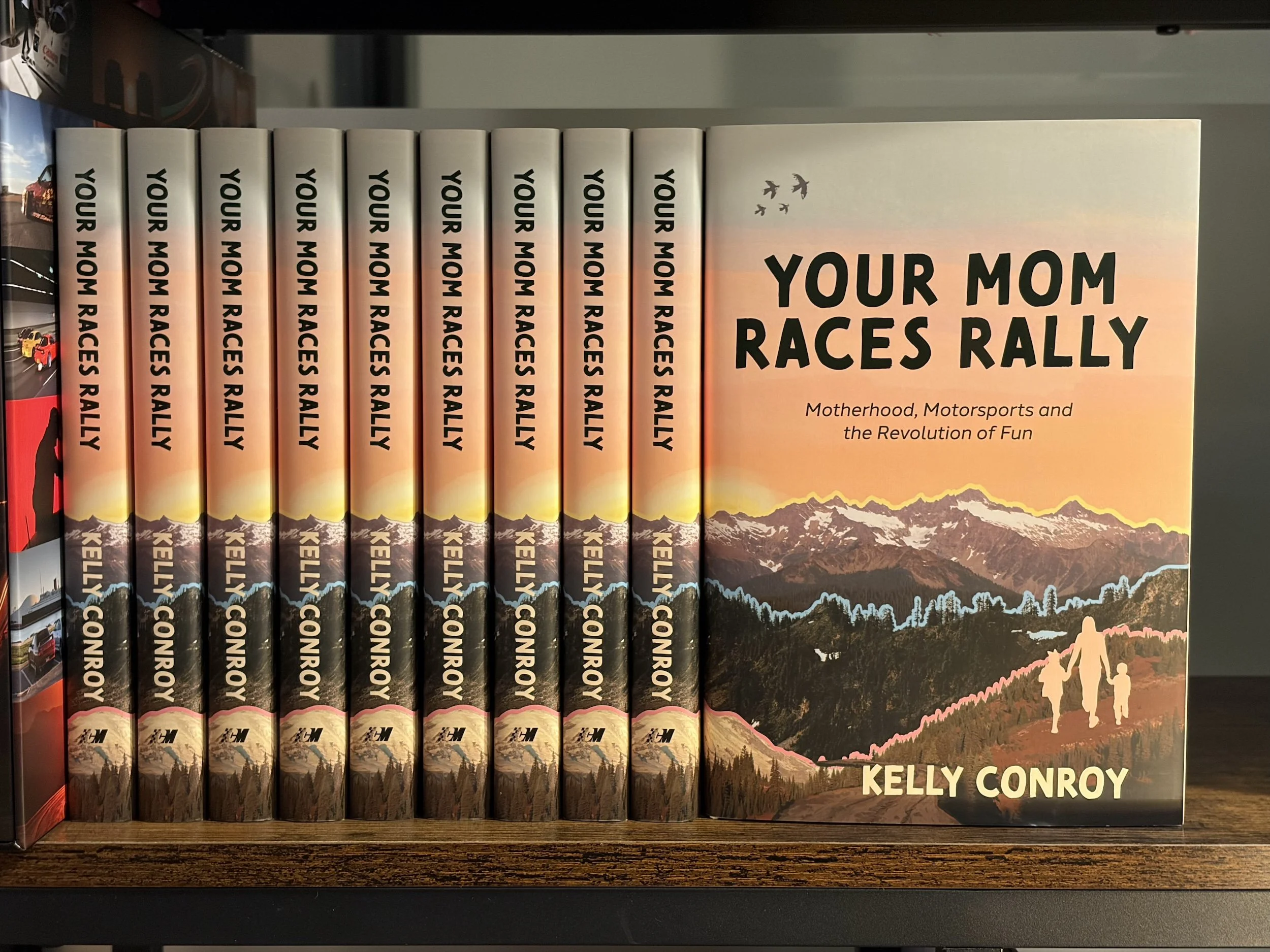 The cover of 'Your Mom Races Rally' by Kelly Conroy, a motorsports memoir about rediscovering your adventurous self after motherhood. Published by Carrara Media, 2026.