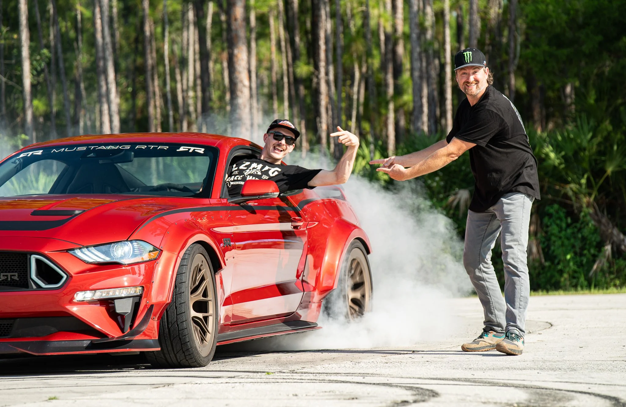 Adam LZ hangs out of the window while doing a burnout in a Ford Mustang RTR Spec 5 as Vaughn Gittin Jr. looks on, featured in the book "Ready To Rock" by Gittin Jr. about the rise of RTR Vehicles. Published by Carrara Media, 2026.