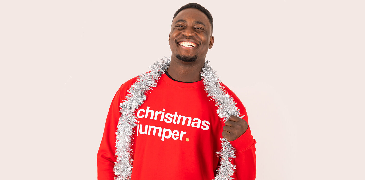 man wearing red christmas jumper holding tinsel