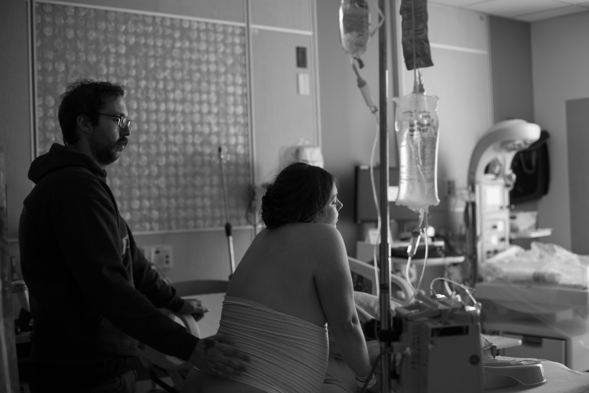 Black and white image of a man giving counter pressure to a woman in the hospital. 