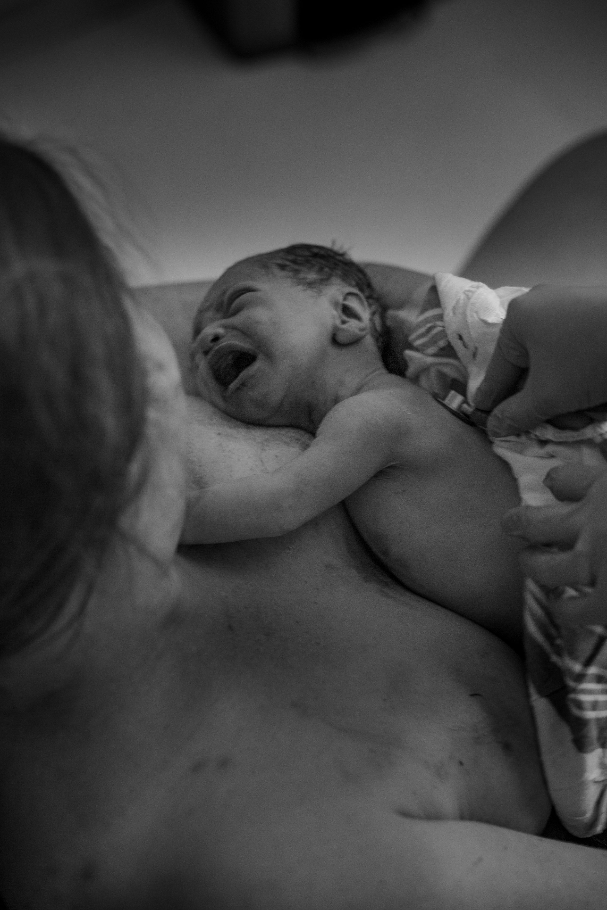 naked newborn baby on his mother's chest.