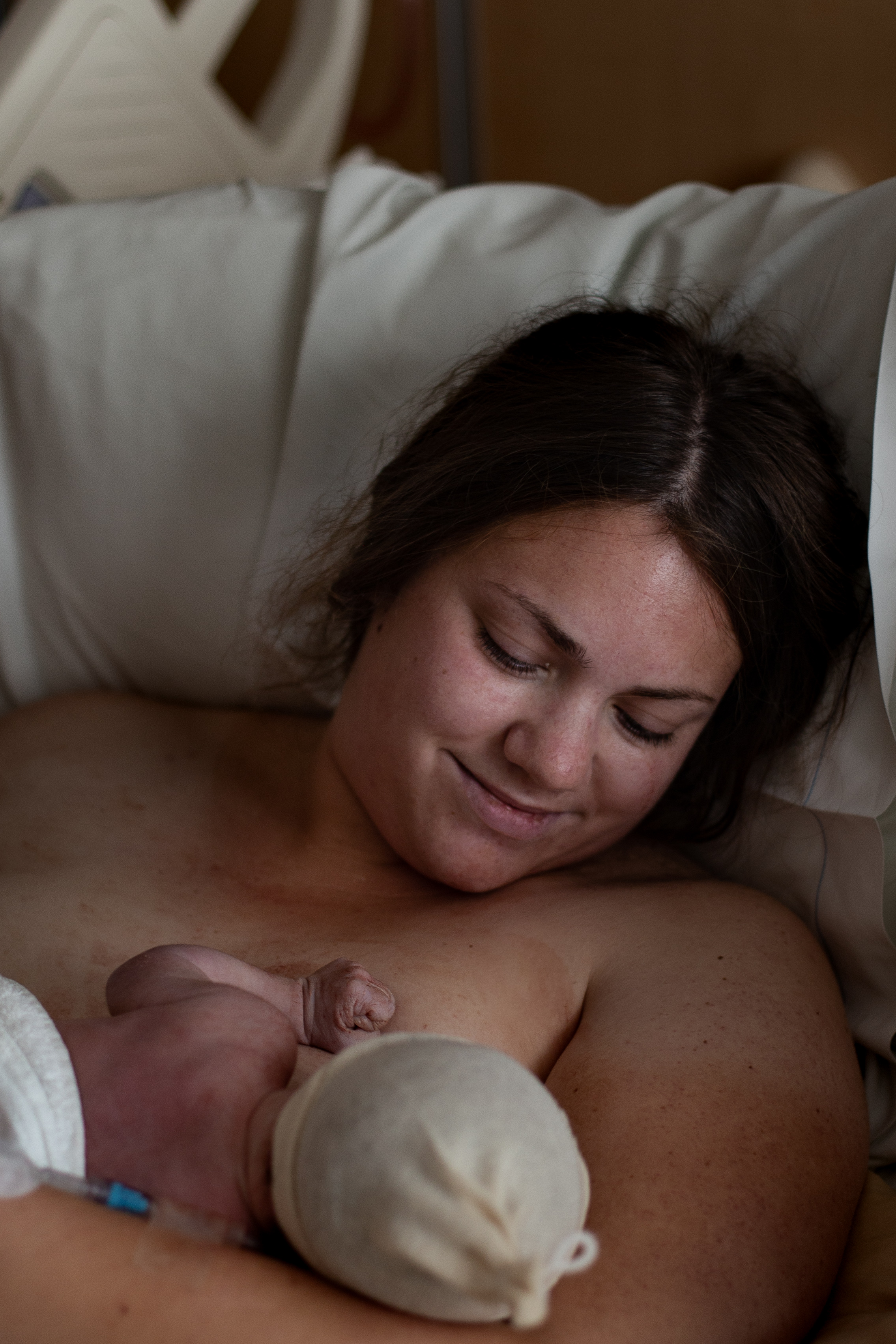 Mother looks down at breastfeeding newborn. 