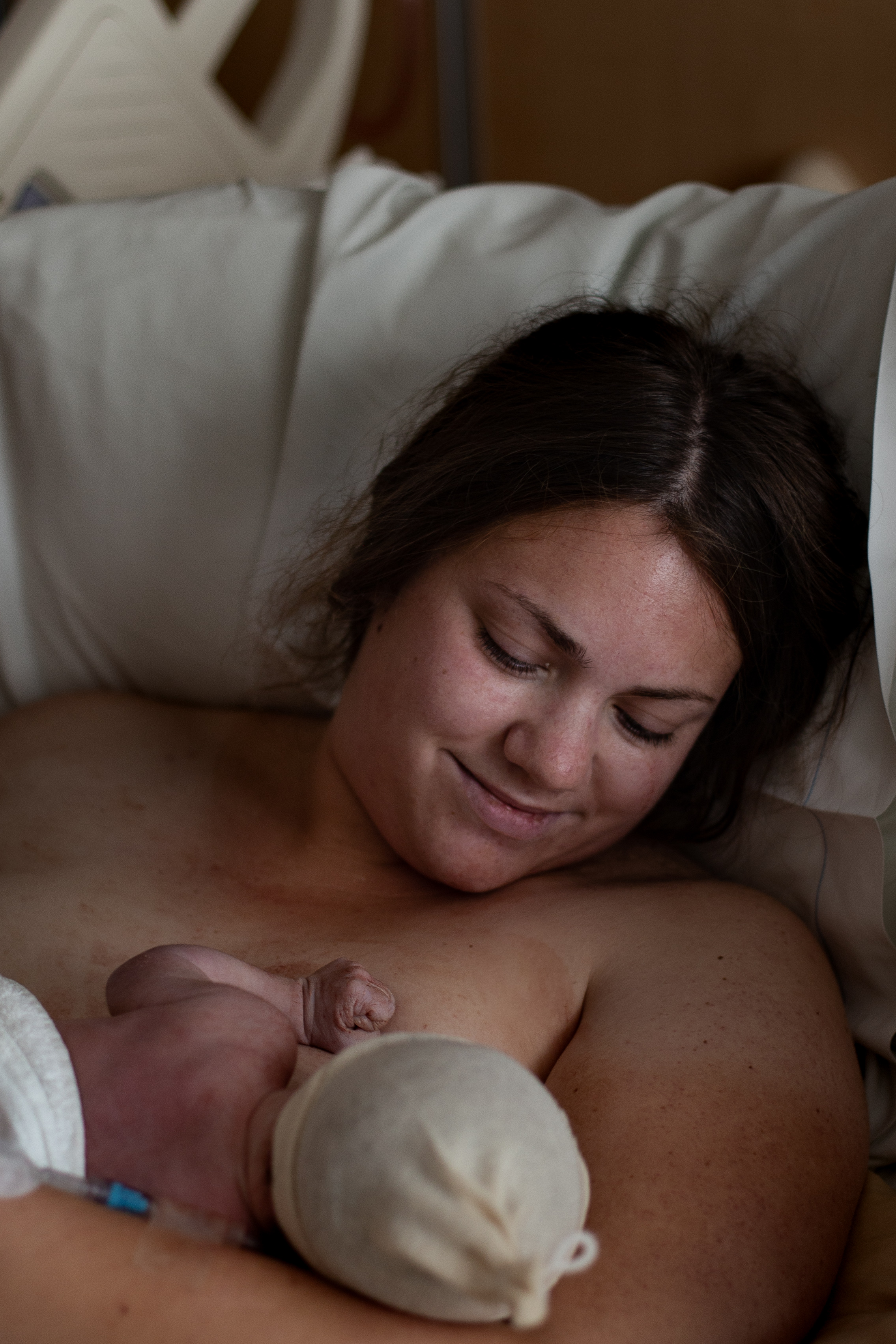 Mother looks down at breastfeeding newborn.
