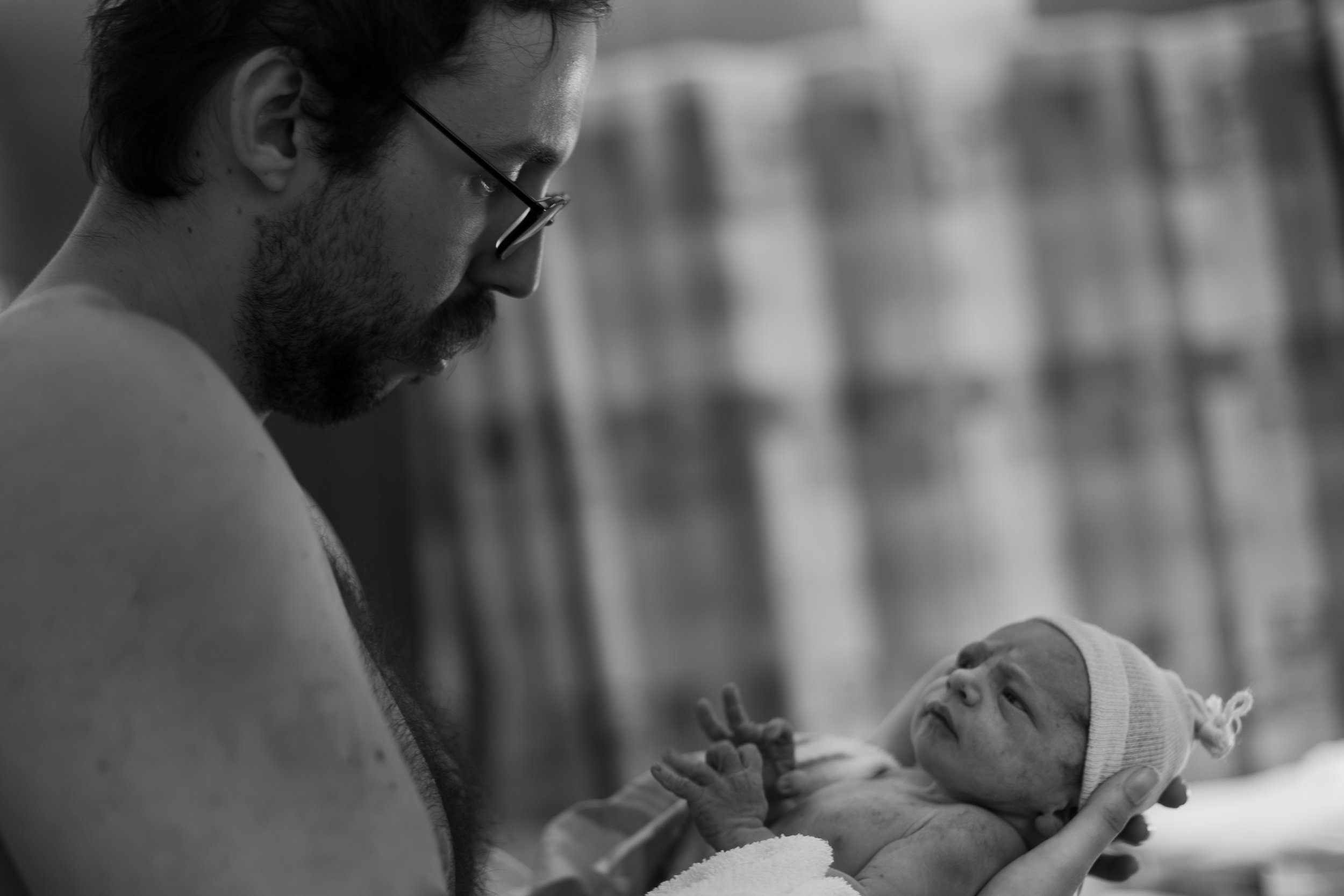 black and white photo of a man holding his newborn baby.