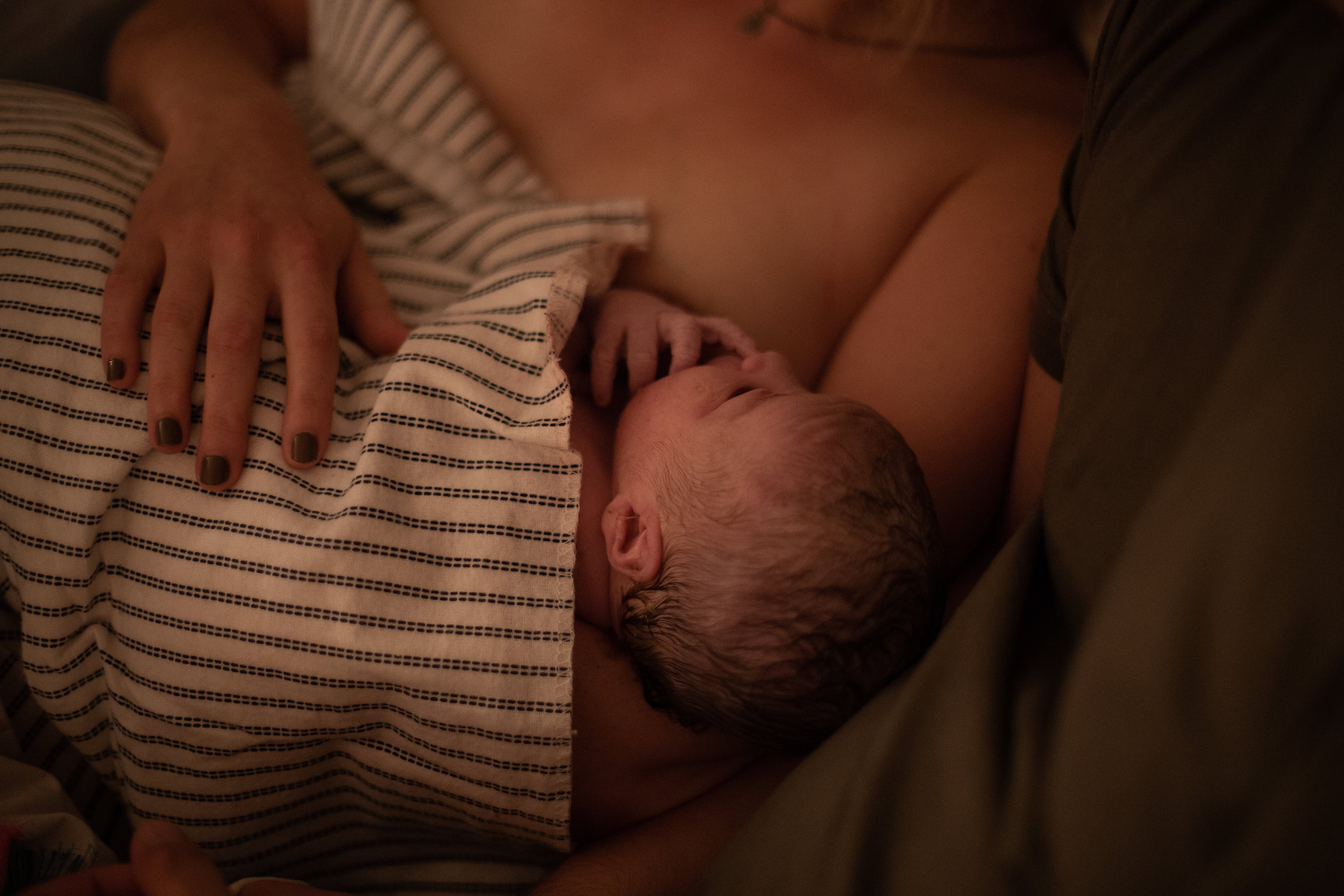 A newborn baby wrapped in a striped receiving blanket.