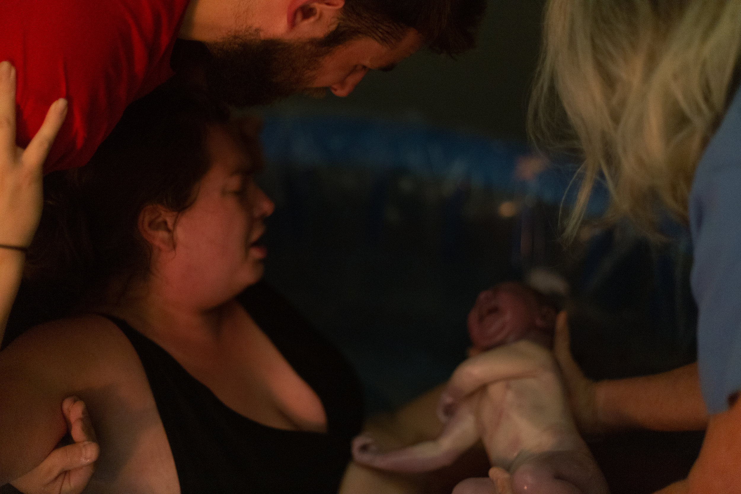A midwife holds up a new baby in a birth pool. 