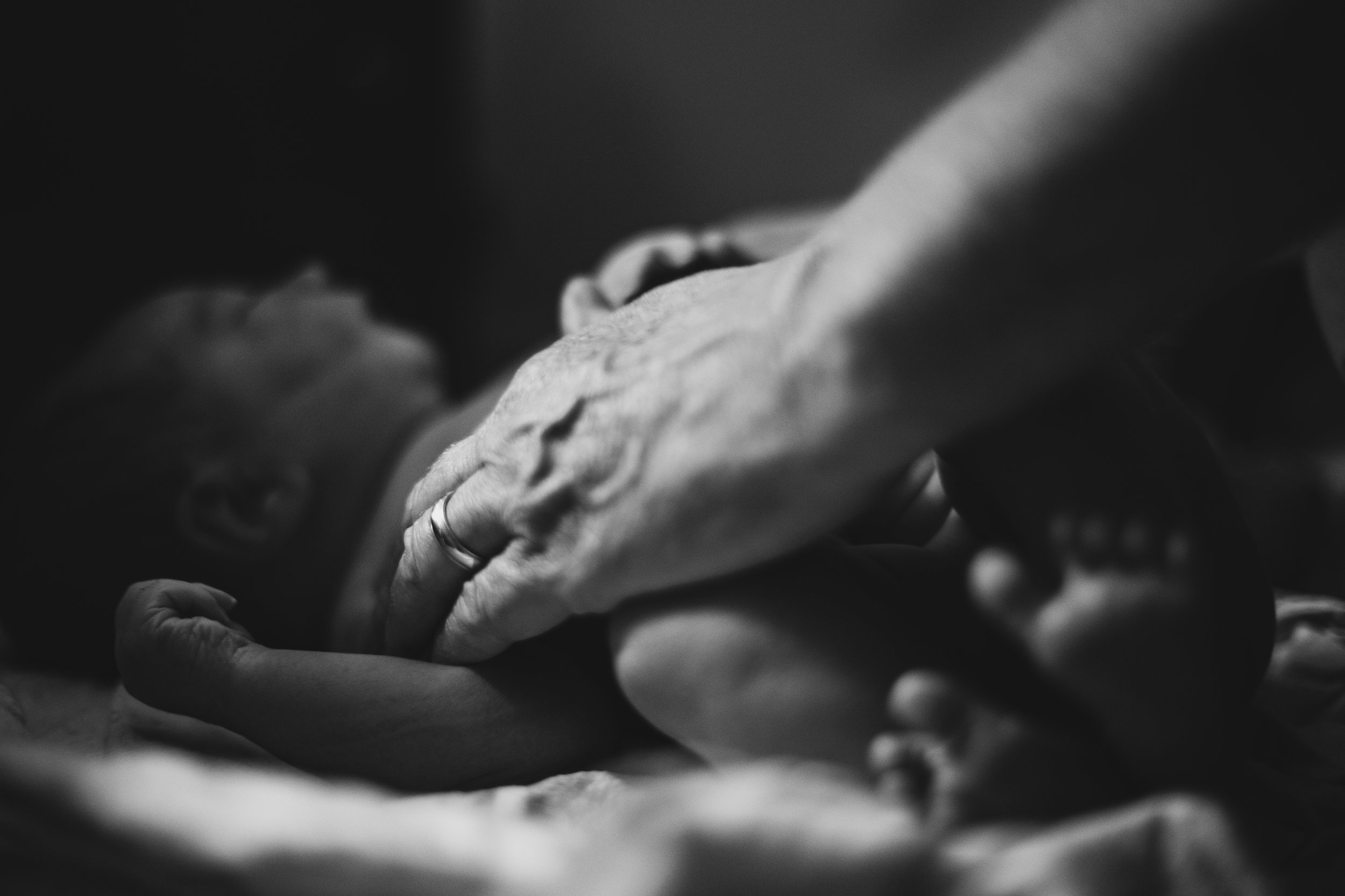 A midwife holds her hand on a newborn baby's chest. 