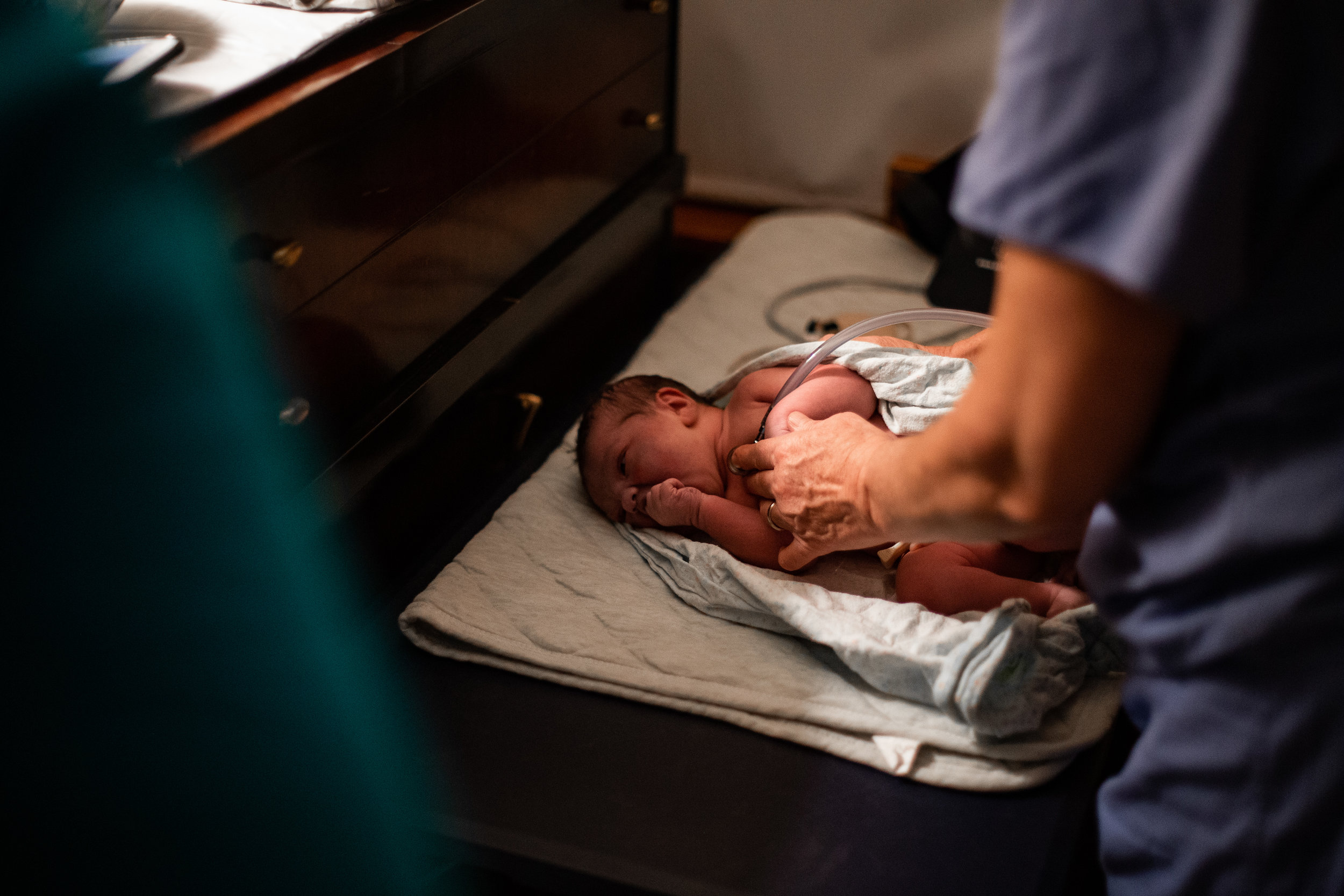 A home birth midwife checks the heart beat of a baby at a home birth.