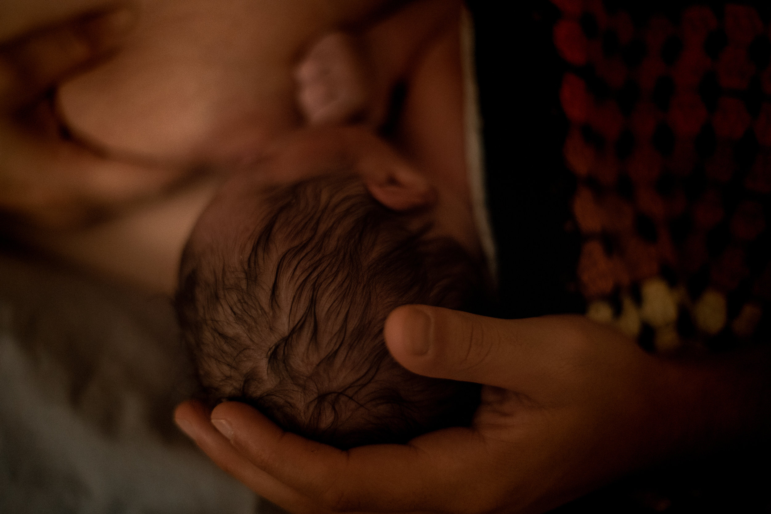 A newborn's head cupped gently by her father. 