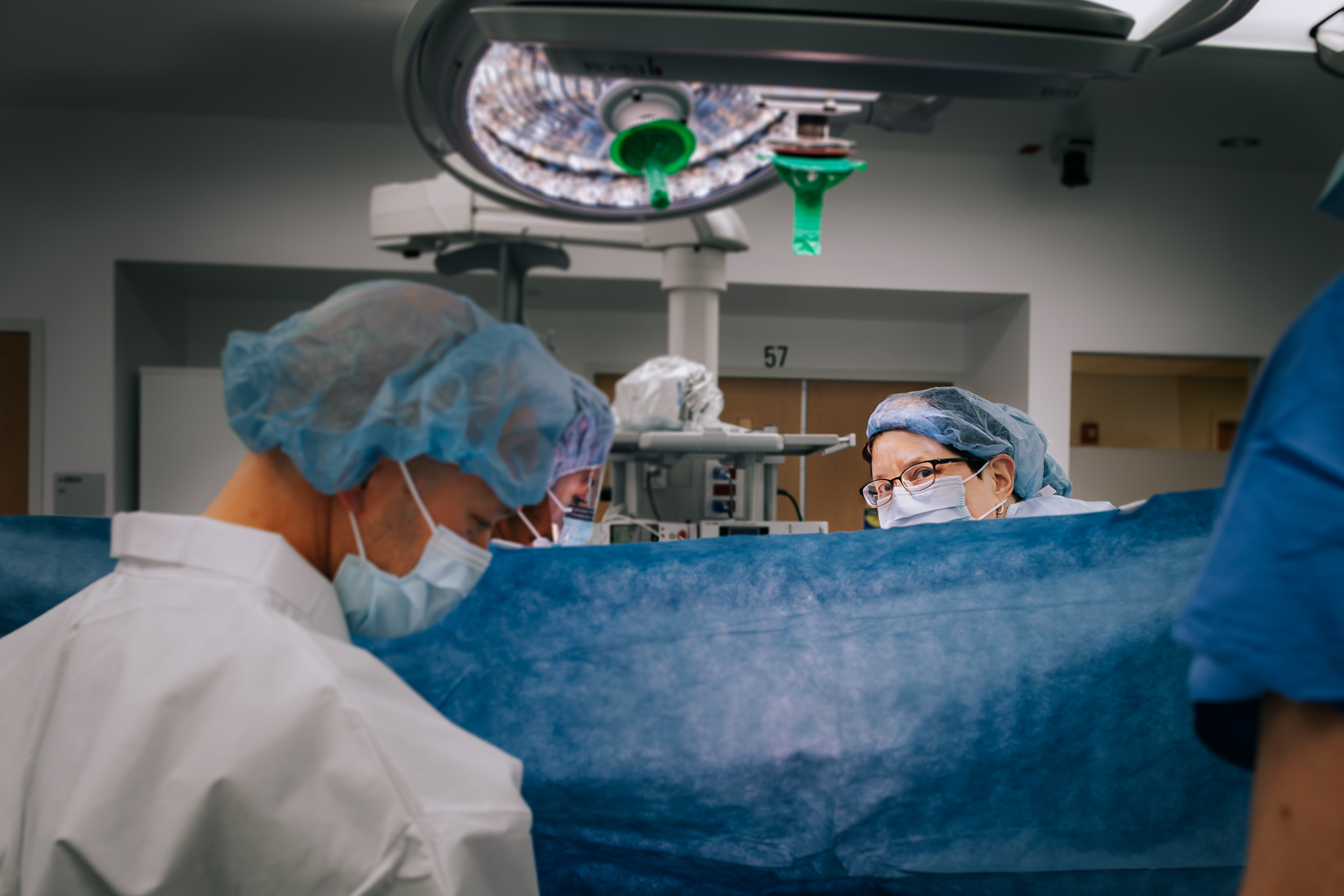 doctor making eye contact with camera before lifting baby above the curtain. 