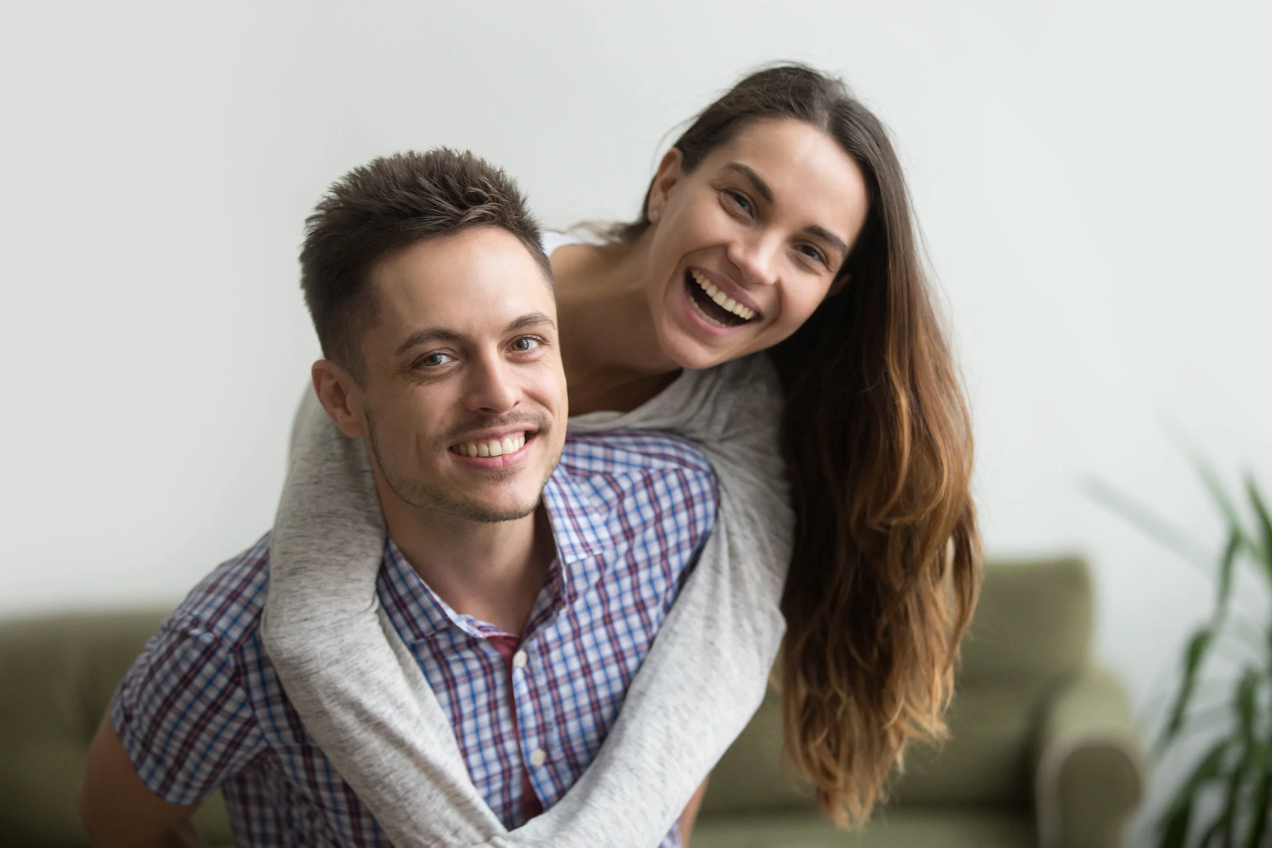 Copy of Smiling husband piggybacking cheerful wife at home, happy couple