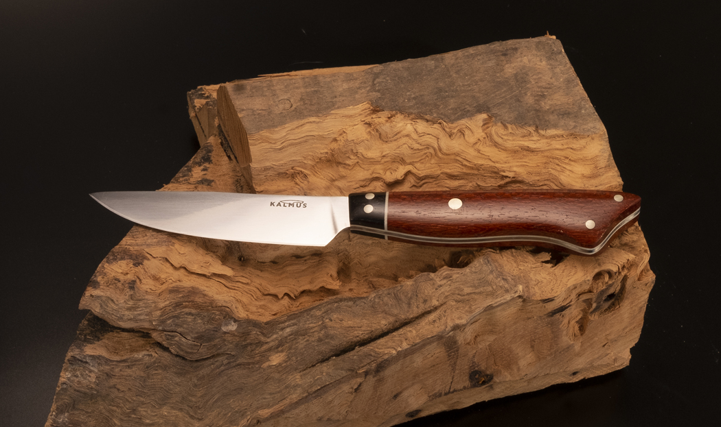 A 4” Paring knife of 440C stainless steel with an overall length of 7-1/2”. This knife has a lacewood handle, Gabon ebony bolster, white G10 liners and spacers and nickel silver pins. A great knife for those small hand-held kitchen tasks.