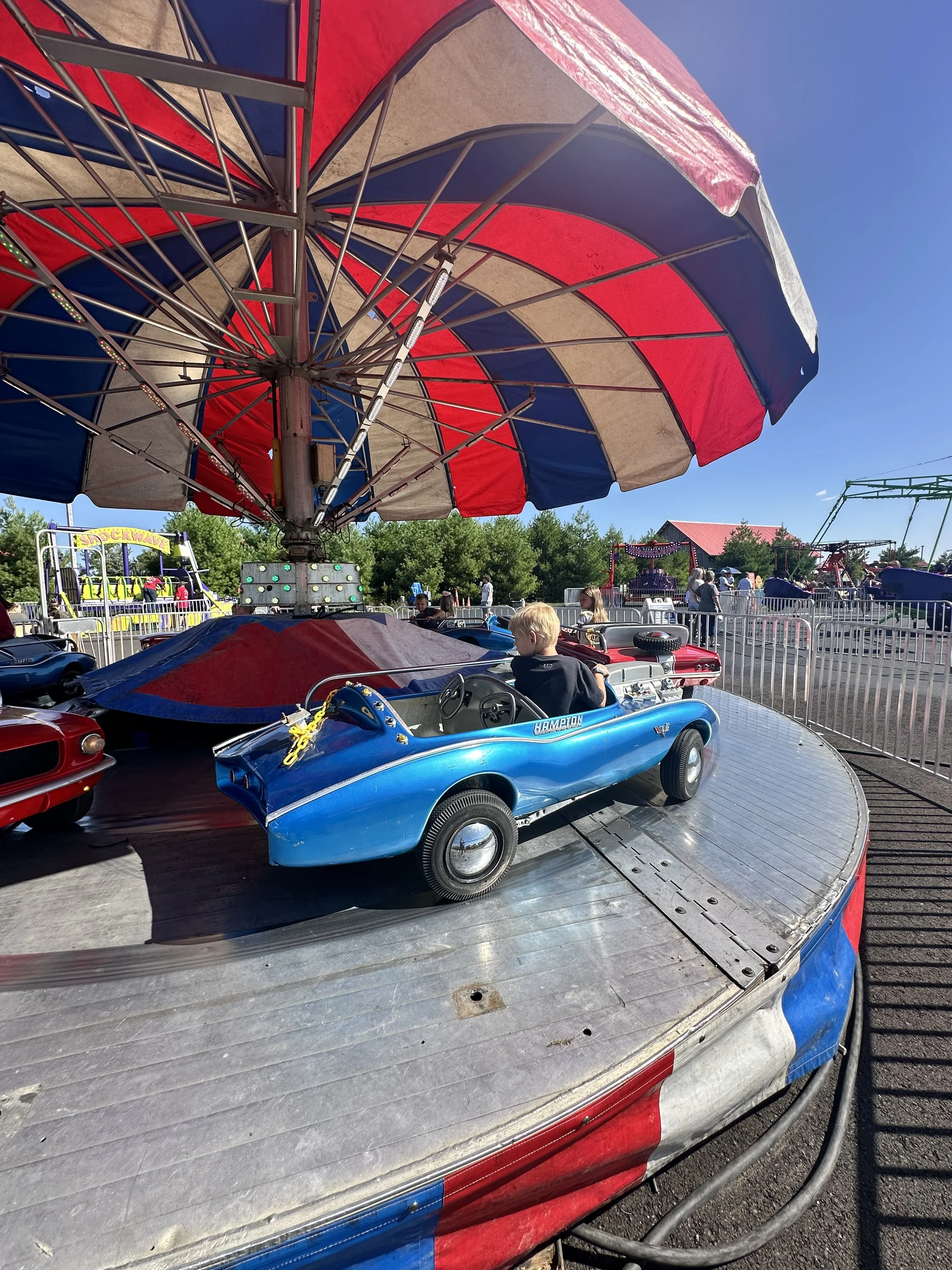 Children riding a blue bumper car at an amusement park.