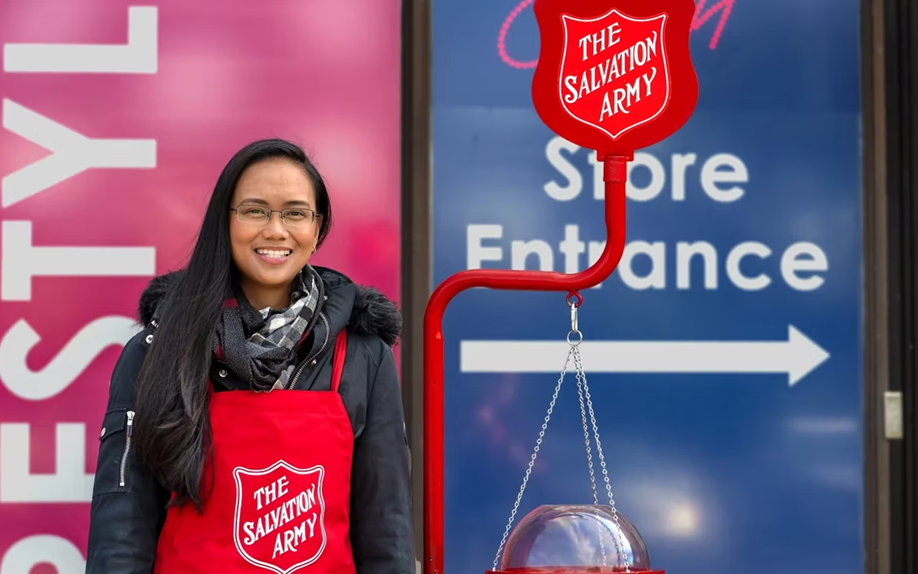 Women standing beside a red kettle.