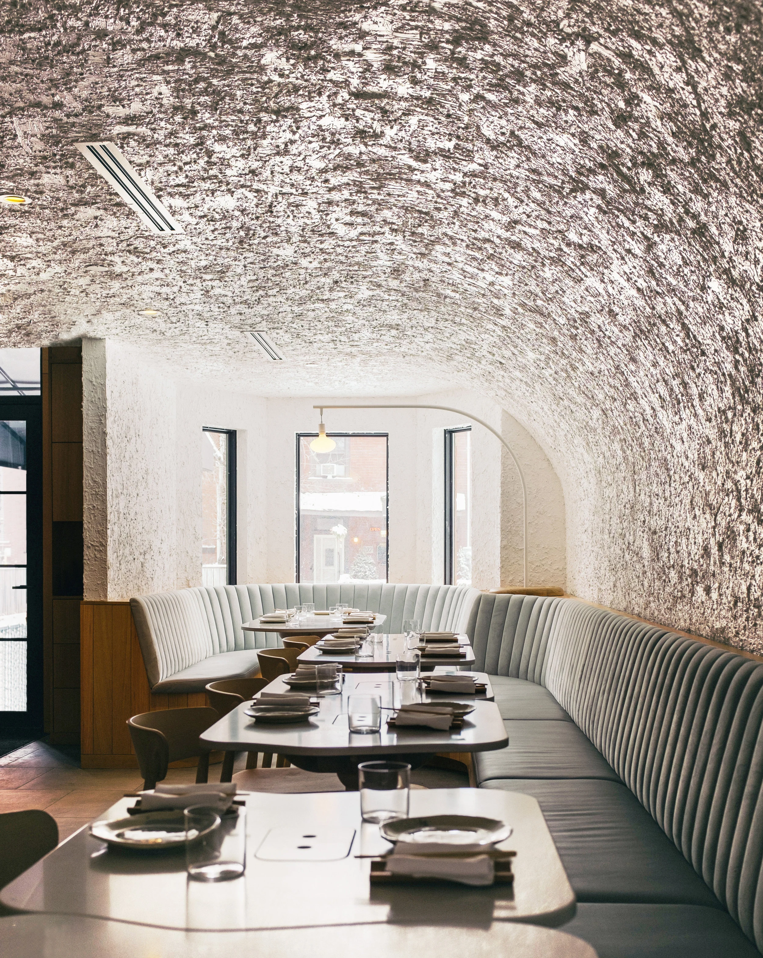 Ground floor dining space with custom tables, textured walls, banquette seating around perimeter