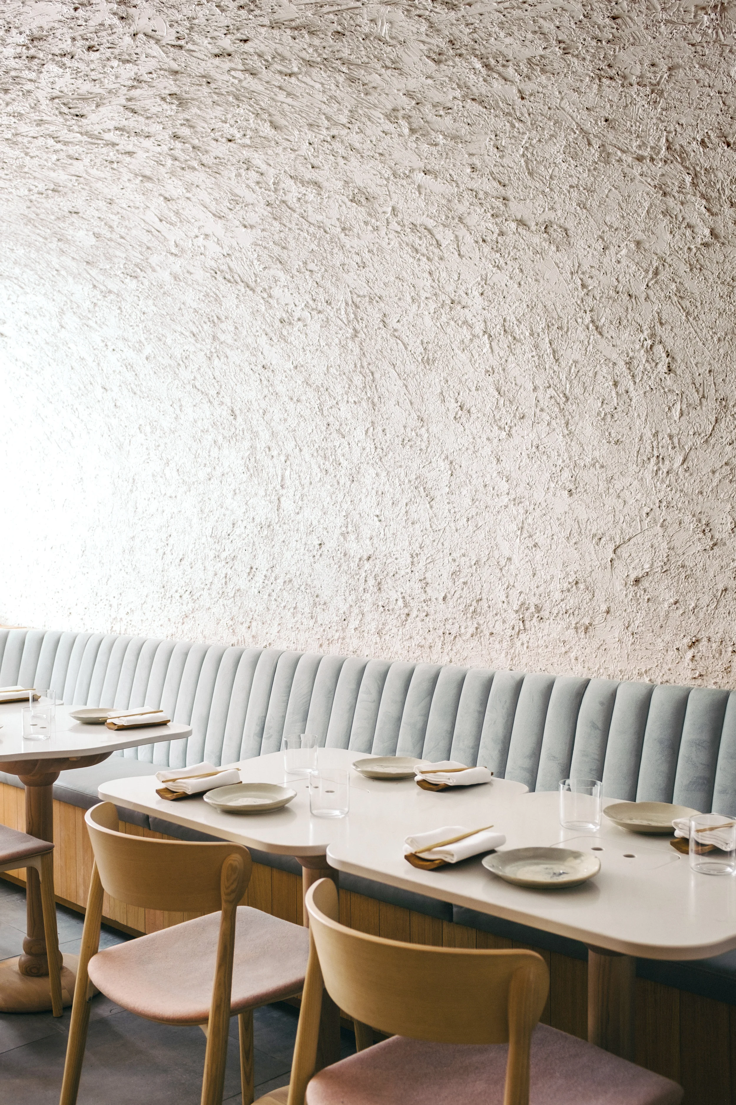 Close up of restaurant table setting with banquette seating, and textured wall in behind.