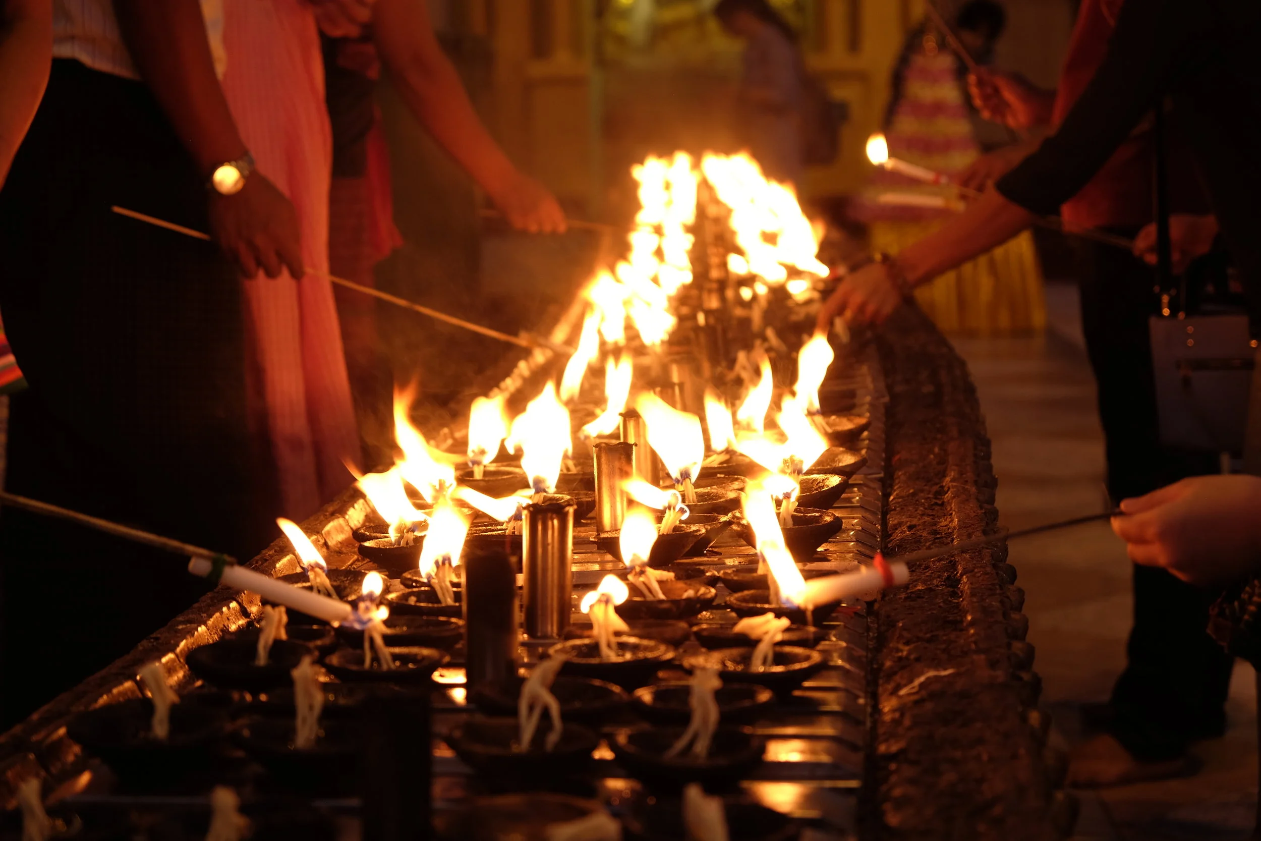 Faithful lighting votives after sunset