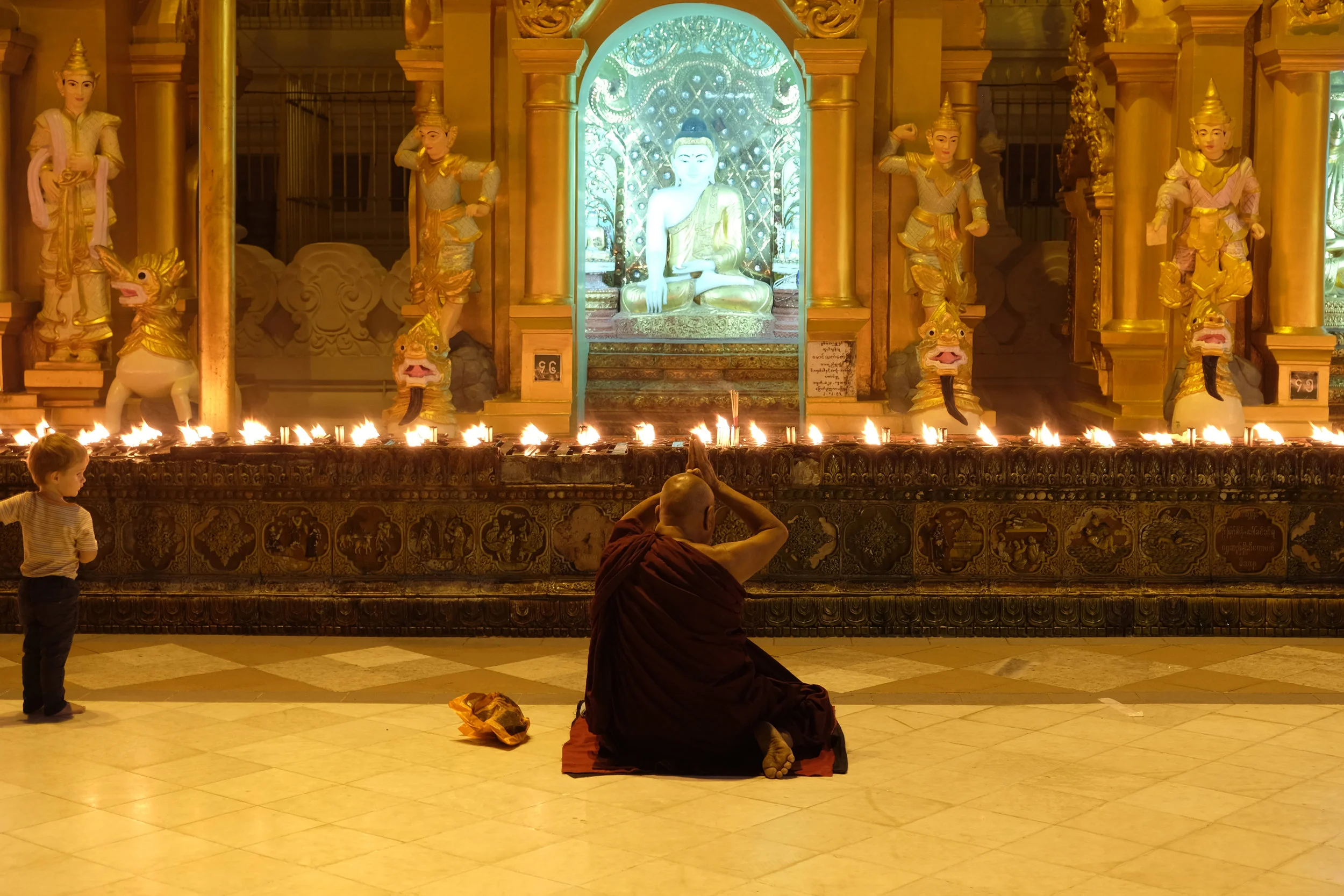 A child looks on as a monk meditates