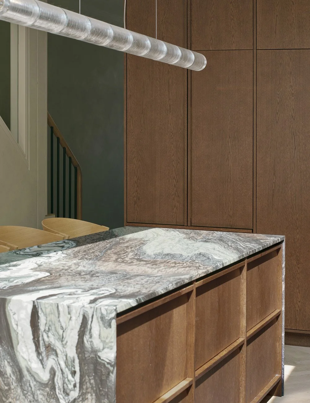Integrerad kyl och frys från Fisher & Paykel bakom minimalistiska köksfronter i mörk ek.