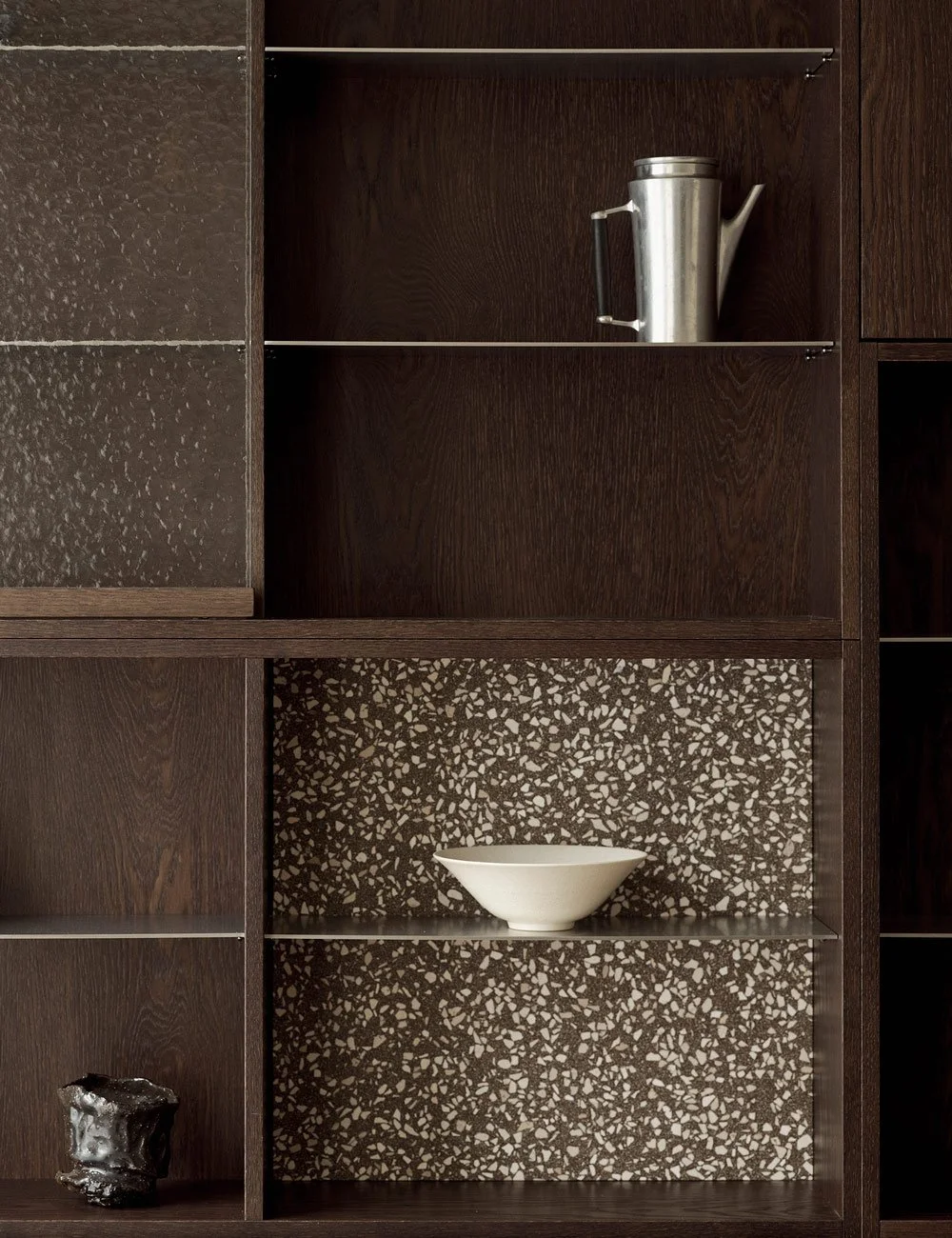 Displayhylla  mörk ek med hamrat glas, terrazzo och hyllplan i rostfritt stål.