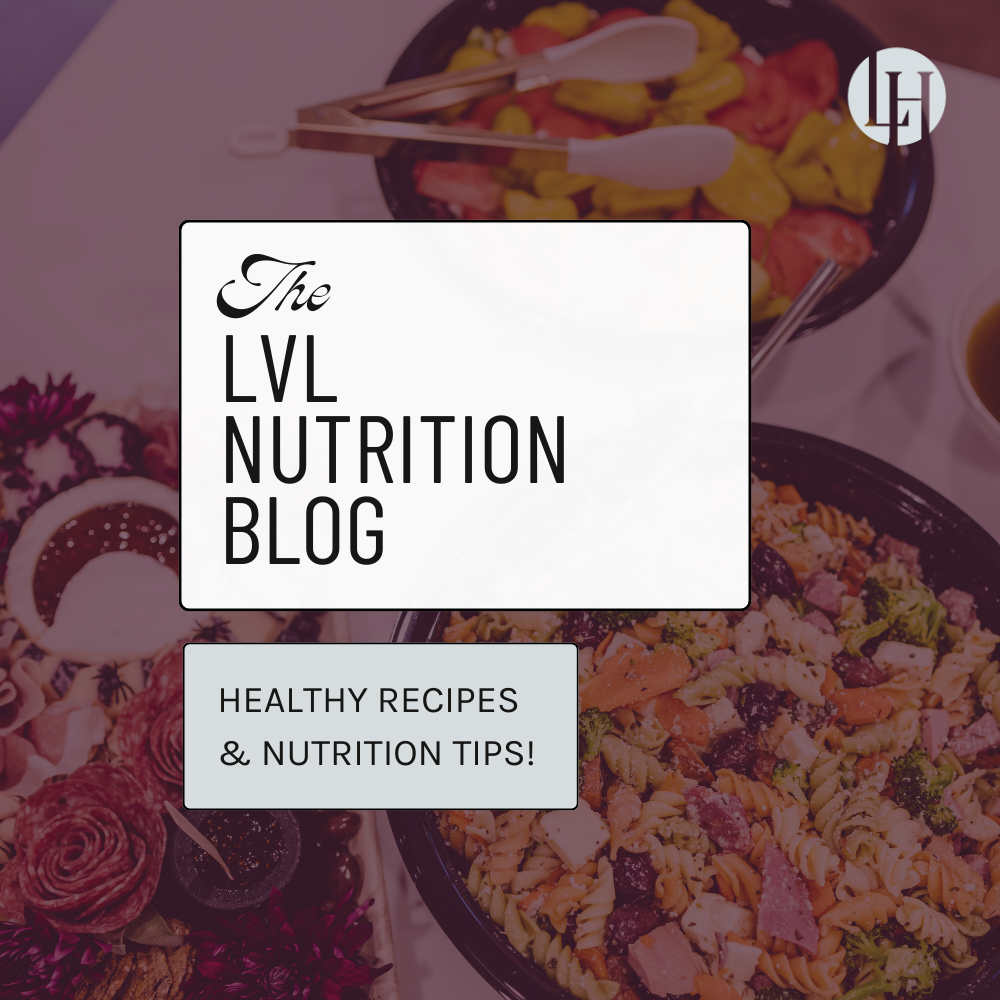 a kitchen counter filled with large platers of pasta salad, charcuterie, and pepper and tomato salad
