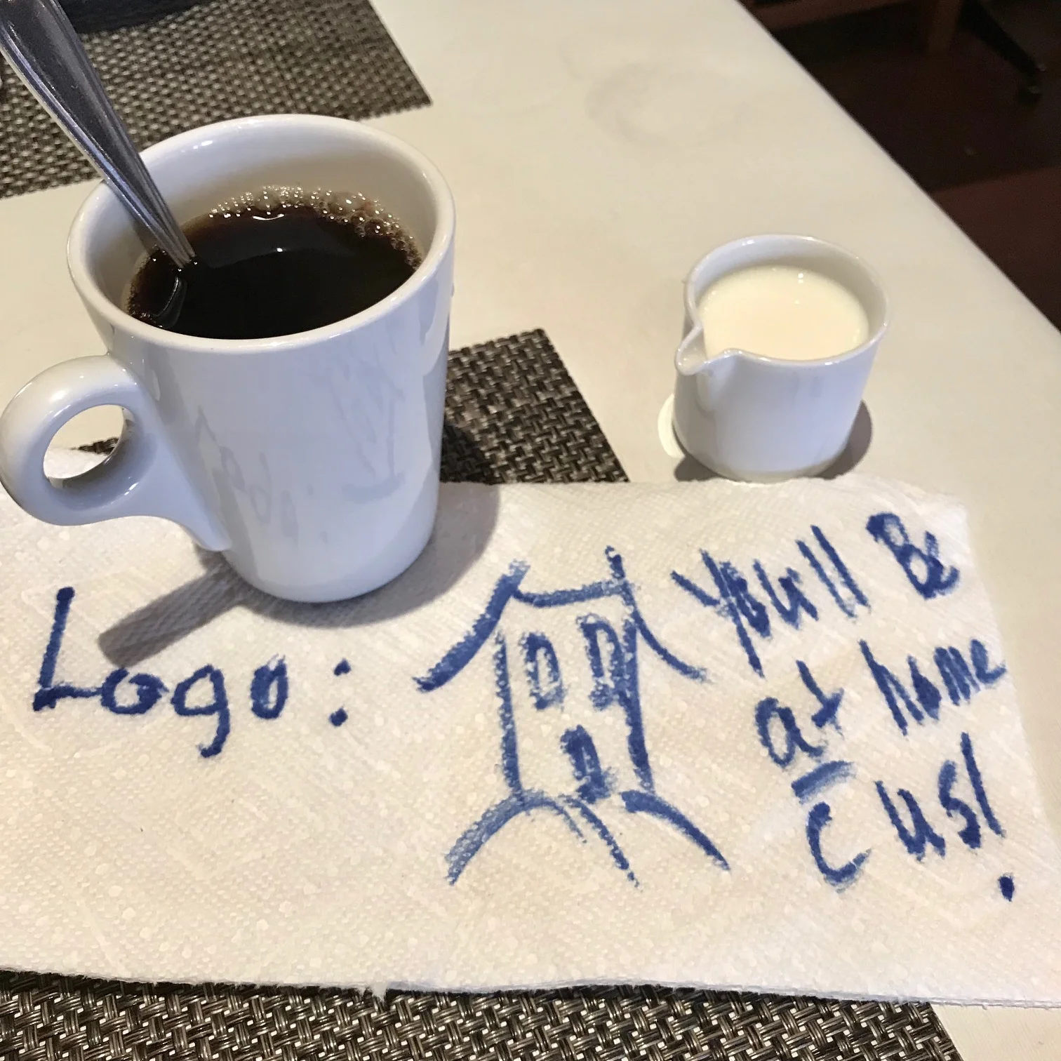 Cup of coffee and napkin with logo drawn on it.