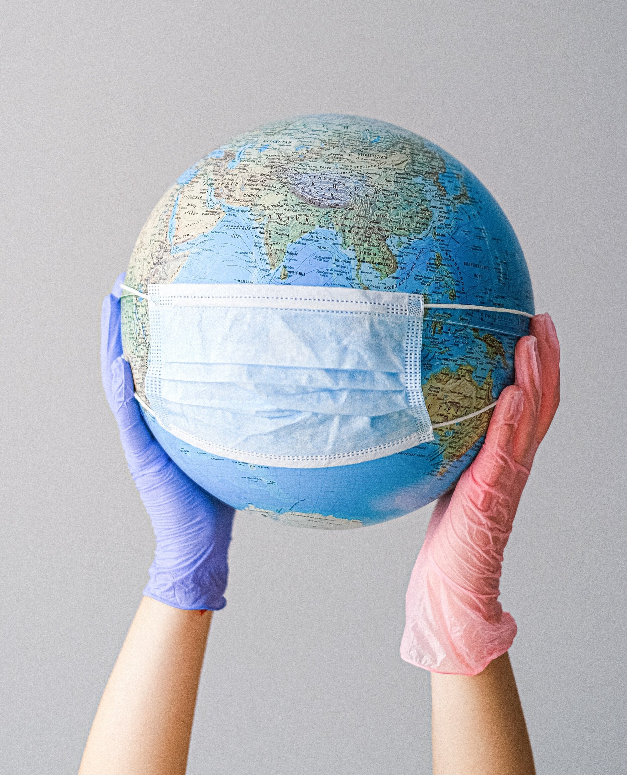 hands-with-latex-gloves-holding-a-globe-with-a-face-mask-4167544.jpg