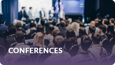 Conferences: attendees seated facing a panel of speakers on a lit stage