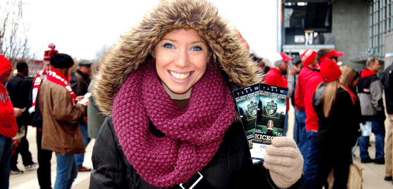 Smiling woman holding event tickets at sporting event.png