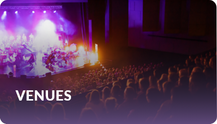 Venues: audience seated in a theater watching a performance under purple stage lighting