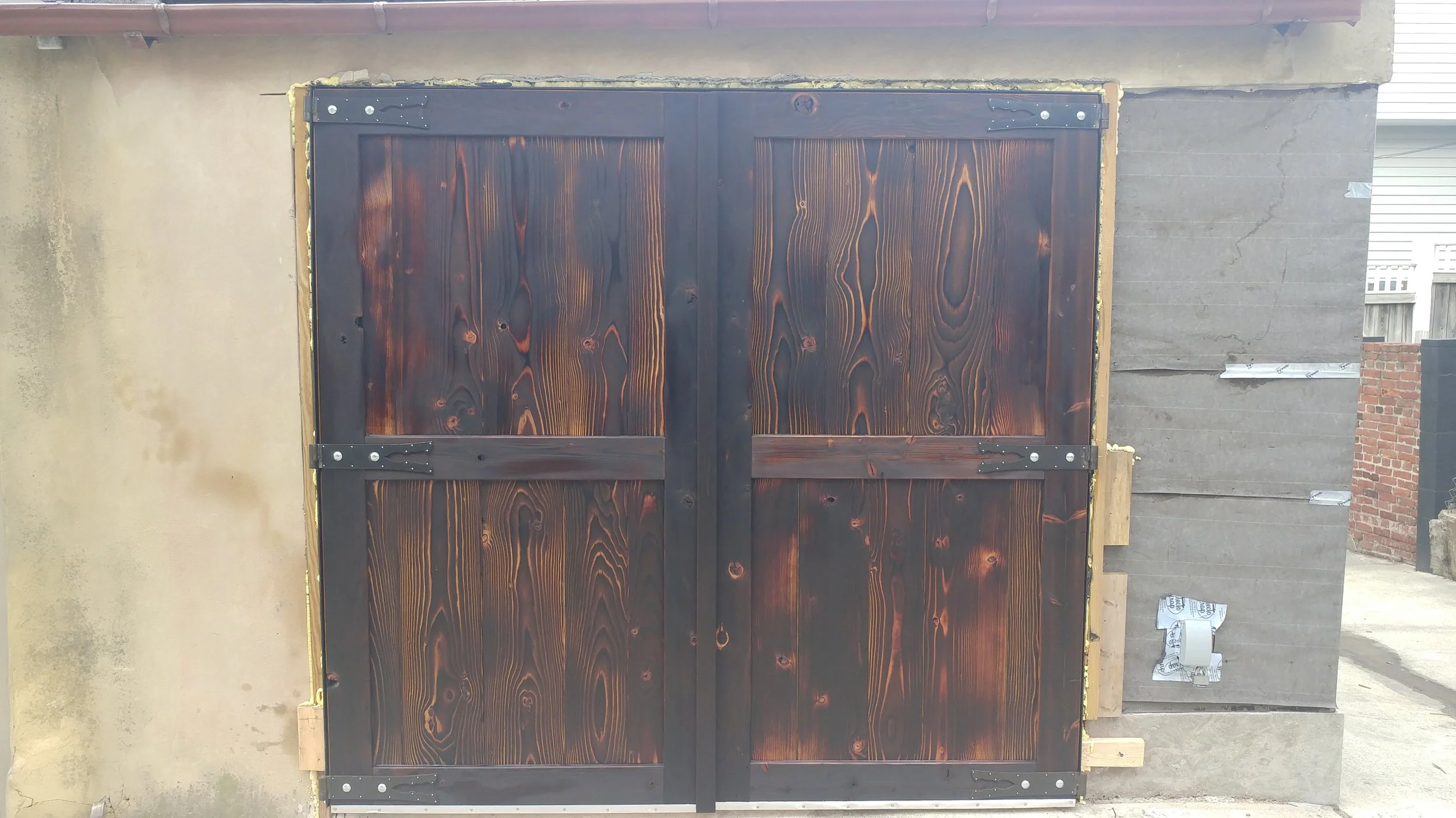 The doors have exteriors which have been charred then oiled. This process is a natural way to waterproof wood. The hinges were inspired by those on the gate to Himeji castle, Japan.