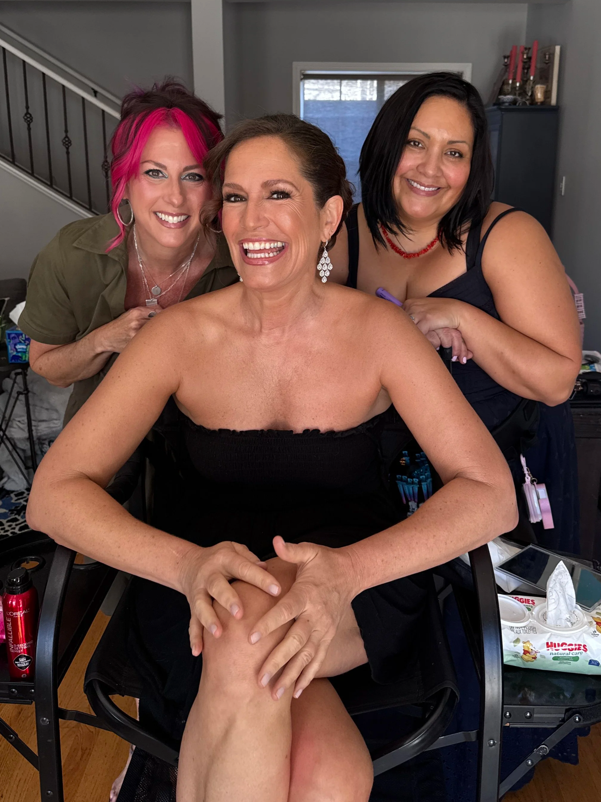 Client sitting in director's chair makeup and hair ready for red carpet event with Hair and Makeup Artist smiling behind her.