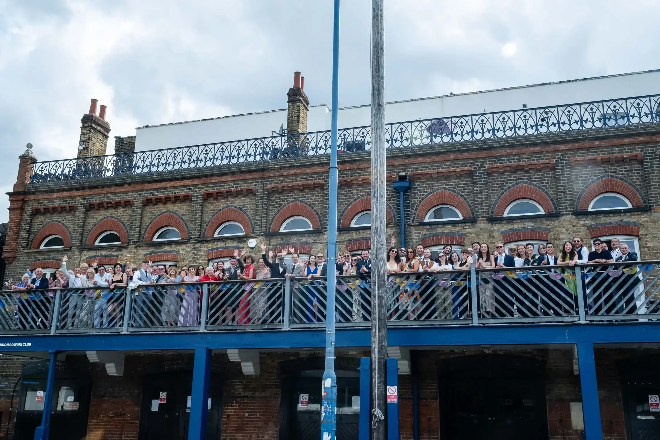 London Rowing Club balcony - crowd of wedding guests waving at camera