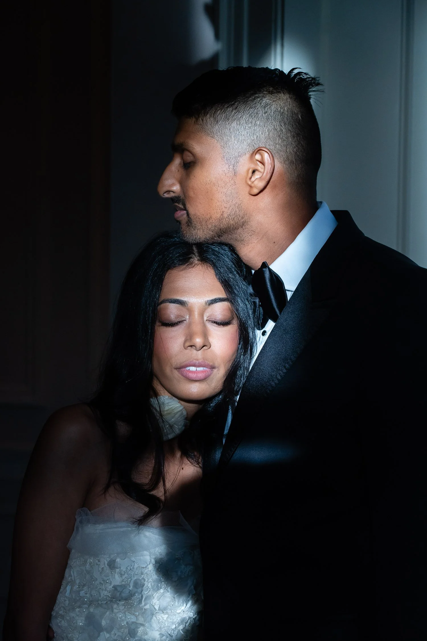 Bride with eyes closed resting head on groom's chest in editorial-style wedding photo