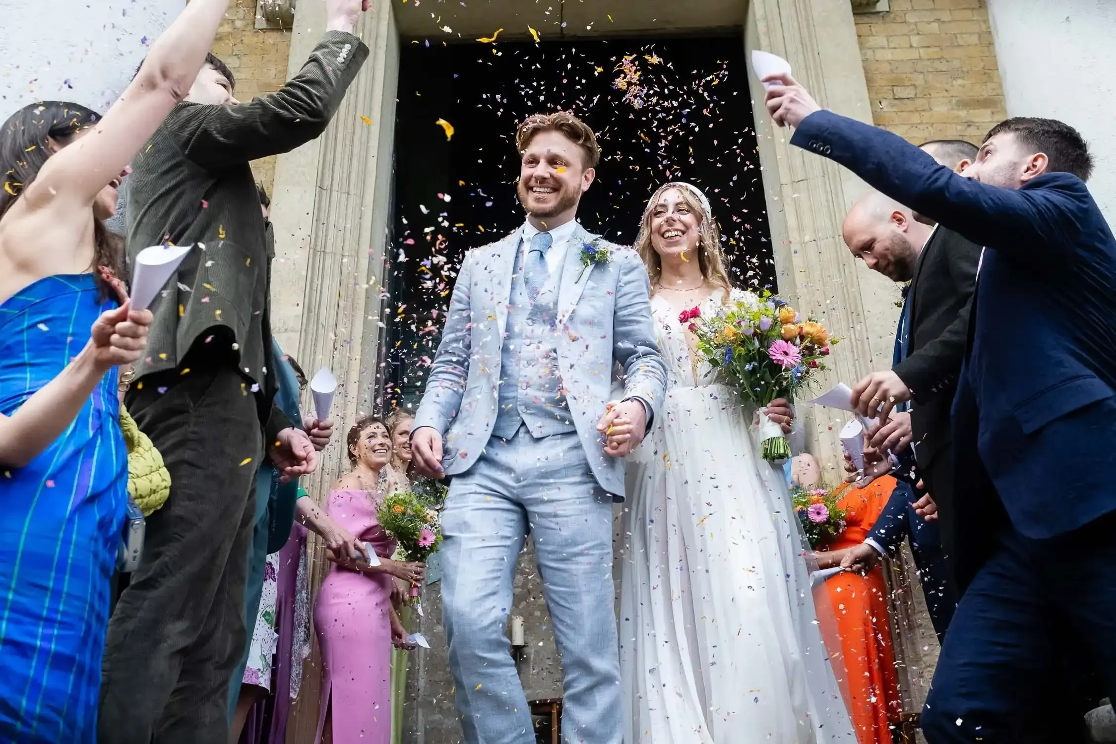 Wedding couple laughing as they exit Asylum Chapel and having confetti thrown all over them
