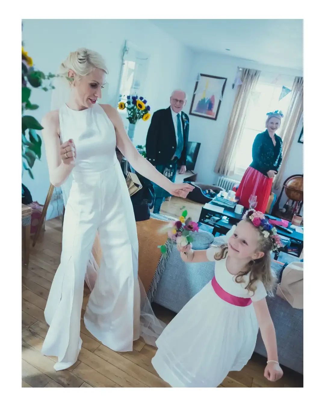 Bride dancing with flower girl at home during bridal preparations