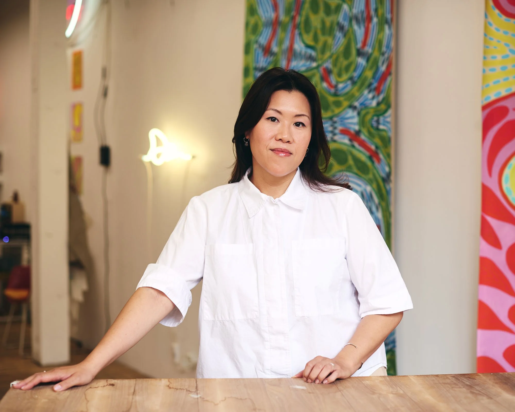 Artist Annesta Le in her Brooklyn, NYC Studio with her abstract neon artwork and 10 ft paintings behind her.