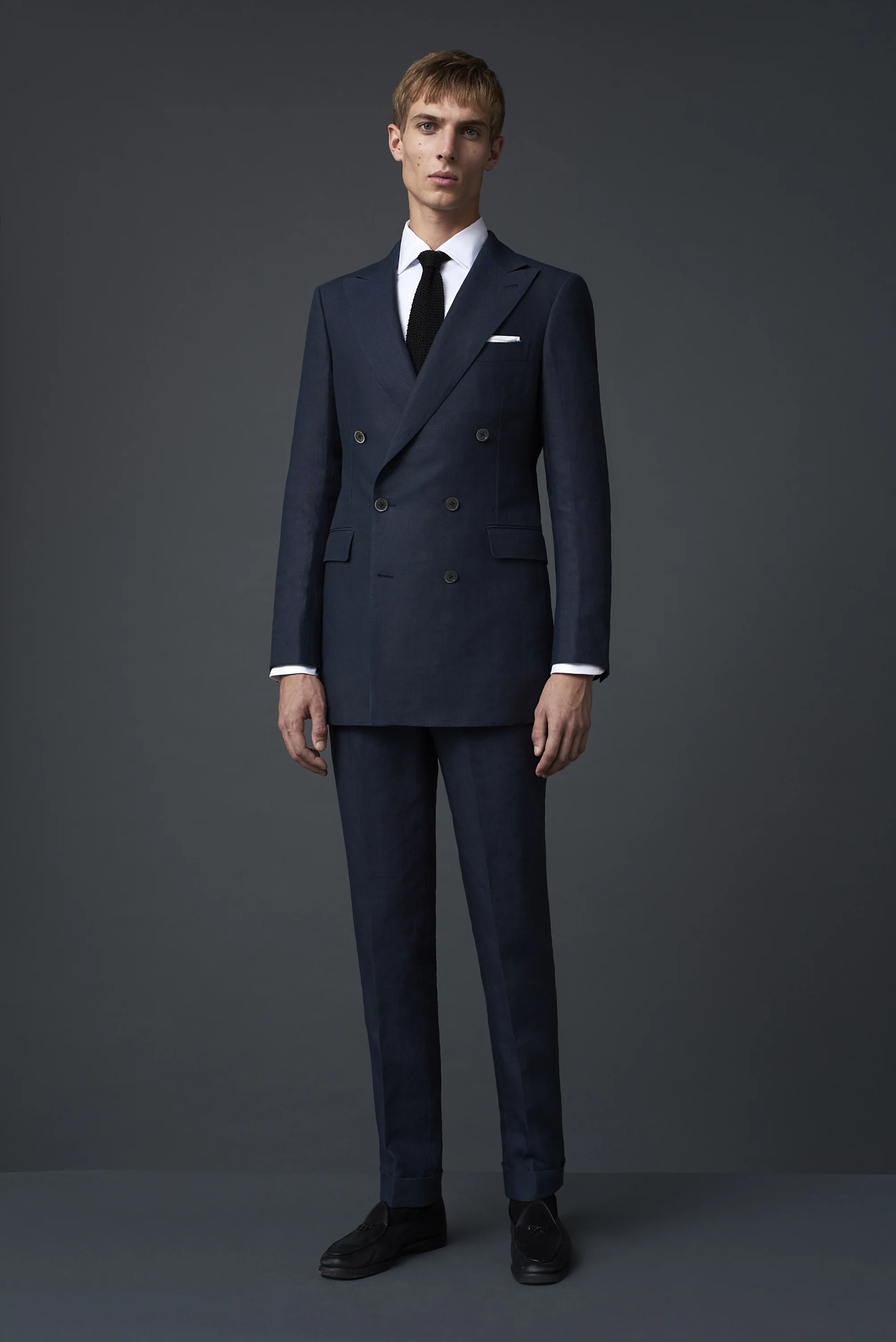 Navy linen 6x2 classic double breasted suit with grey Australian mother of pearl buttons. Worn with a white Egyptian cotton shirt and a black silk knitted tie, made in Como, Italy.