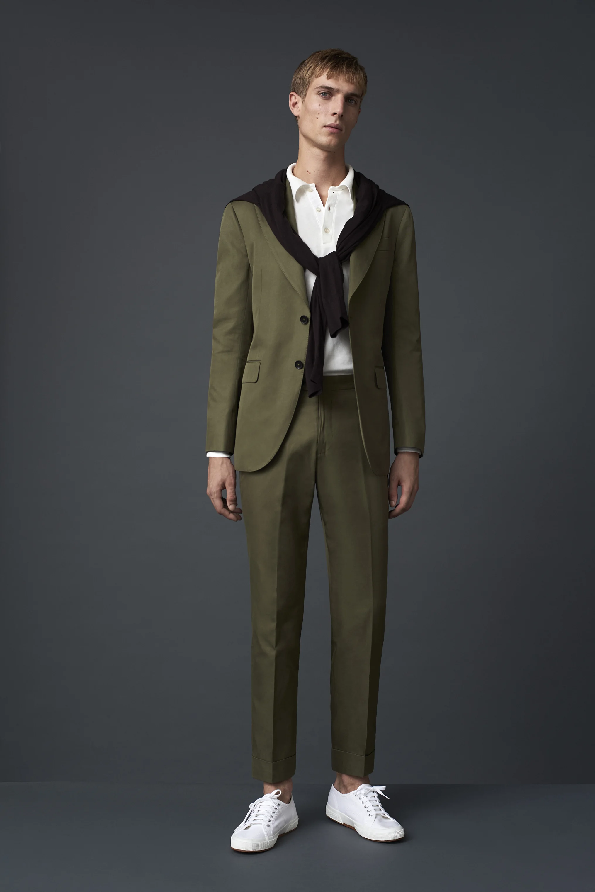 Army green cotton suit with a peak lapel, worn with a P Johnson cream cotton polo and a P Johnson S160 merino knit over the shoulders.