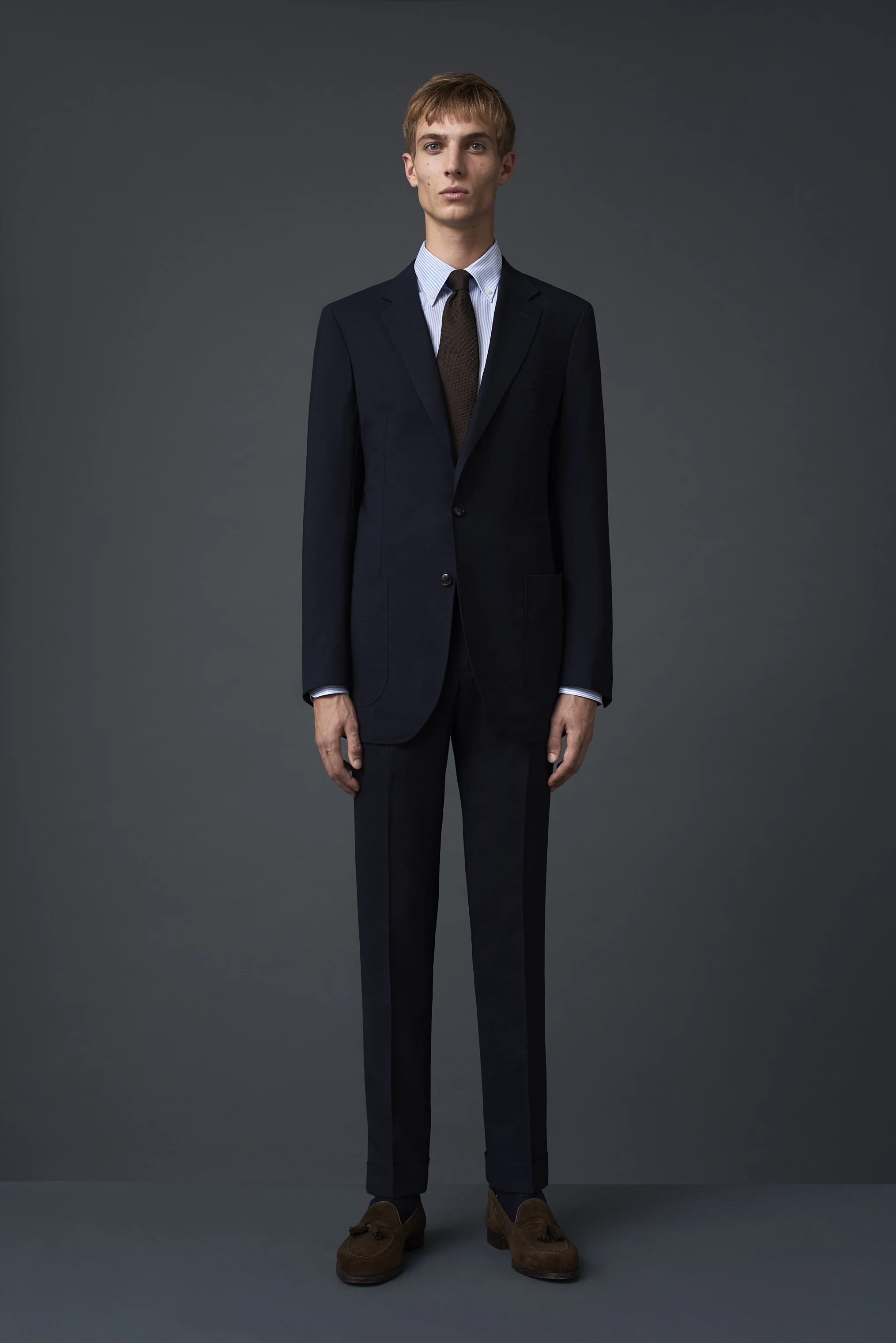 Navy fresco three ply suit with a notch two button lapel and two patch pockets, from merino wool woven in Huddersfield. Paired with a pin point cotton stripe shirt woven in Bergamo and a chocolate brown silk twill tie.