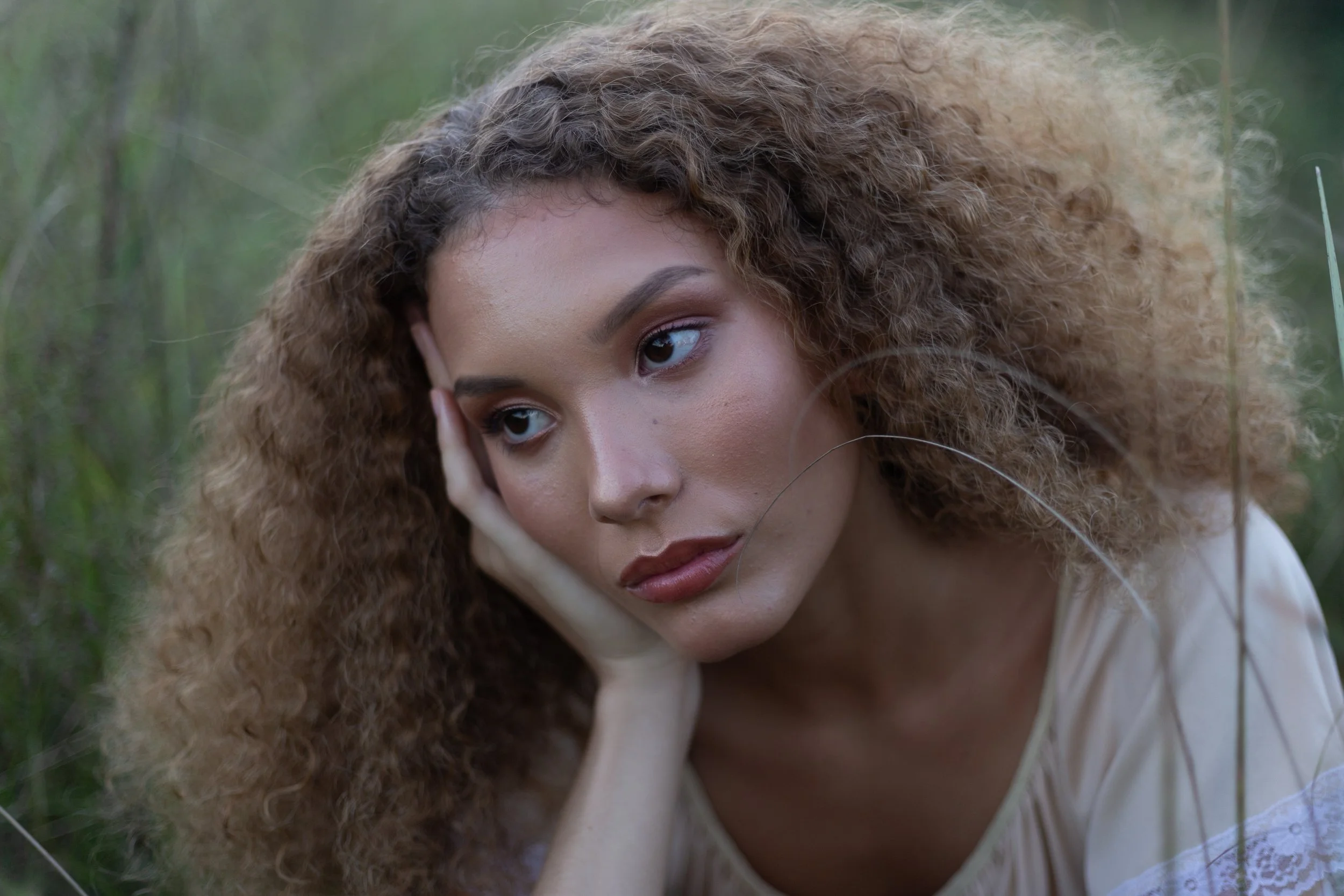 Close up portrait of a woman with long curly hair and her head rested on her hand edited with Archipelago Lightroom Presets